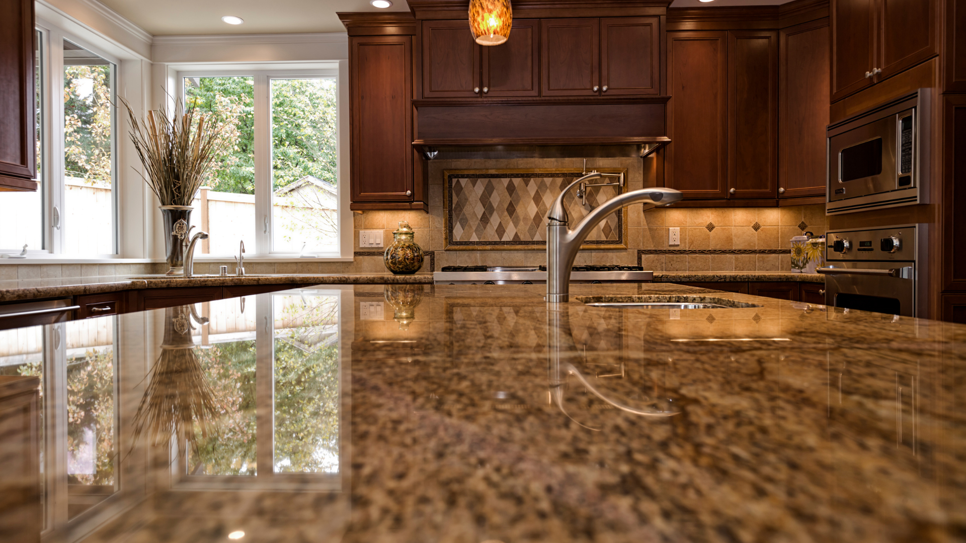 Granite countertop in a kitchen, reflecting light and surrounding elements, with dark wood cabinets and a window.
