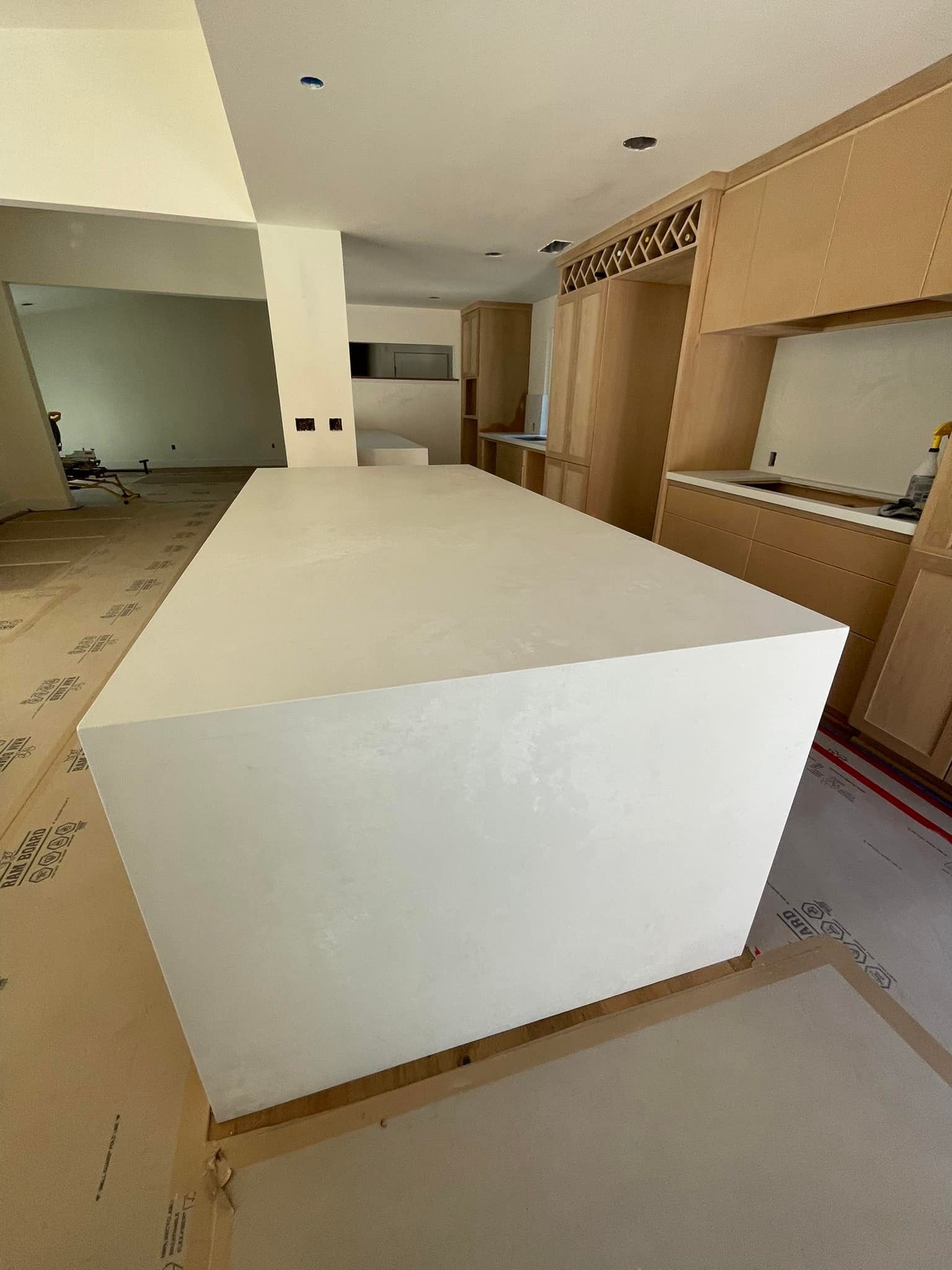 White kitchen island in a light-wood cabinet kitchen under construction.