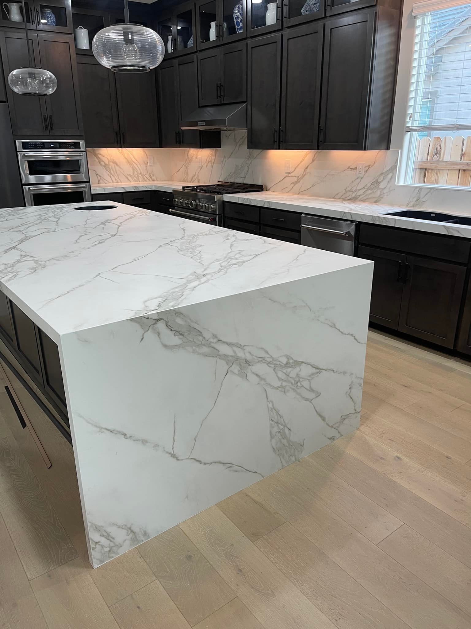 Modern kitchen with white marble countertops and dark gray cabinets.