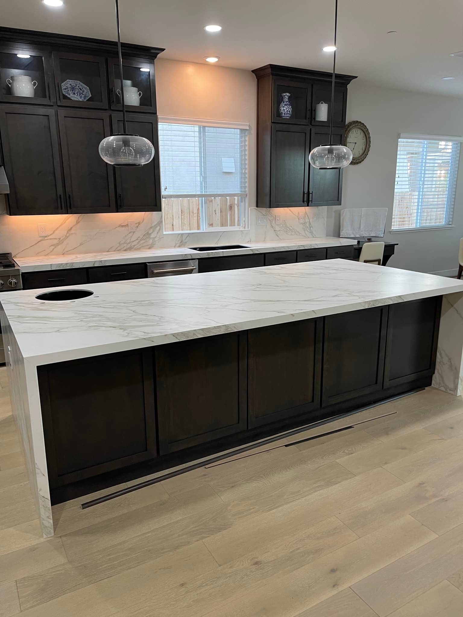 Kitchen with dark cabinets, white countertops, and a large island with a white countertop.