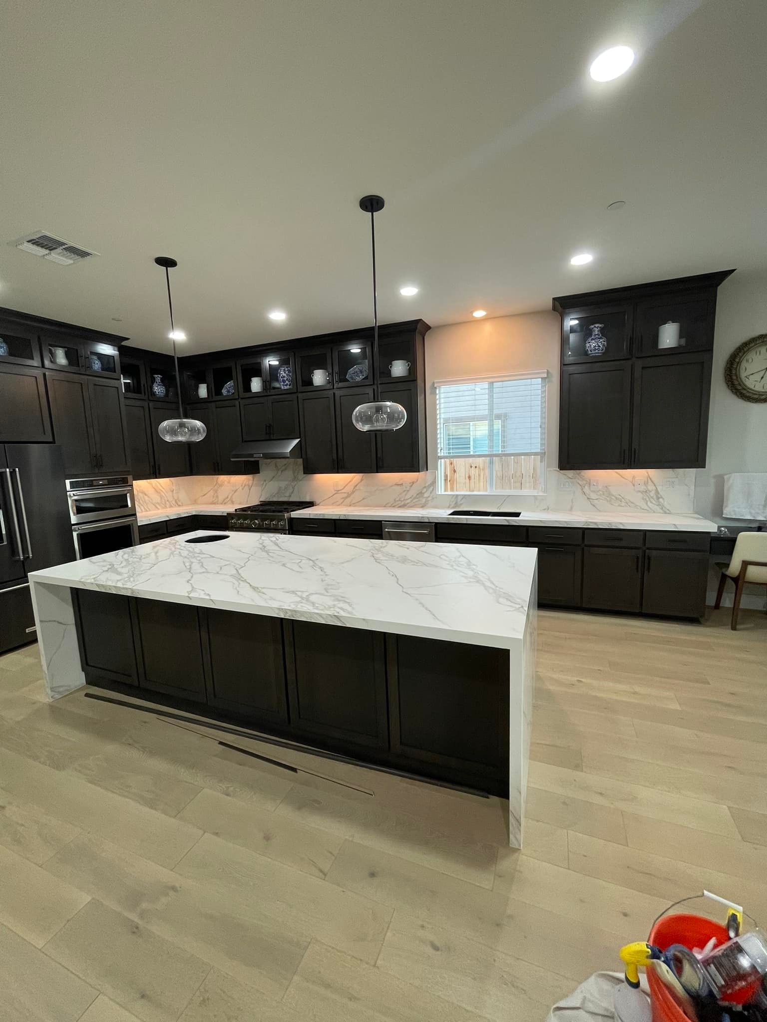 Dark wood kitchen with white countertops and an island; light wood flooring.