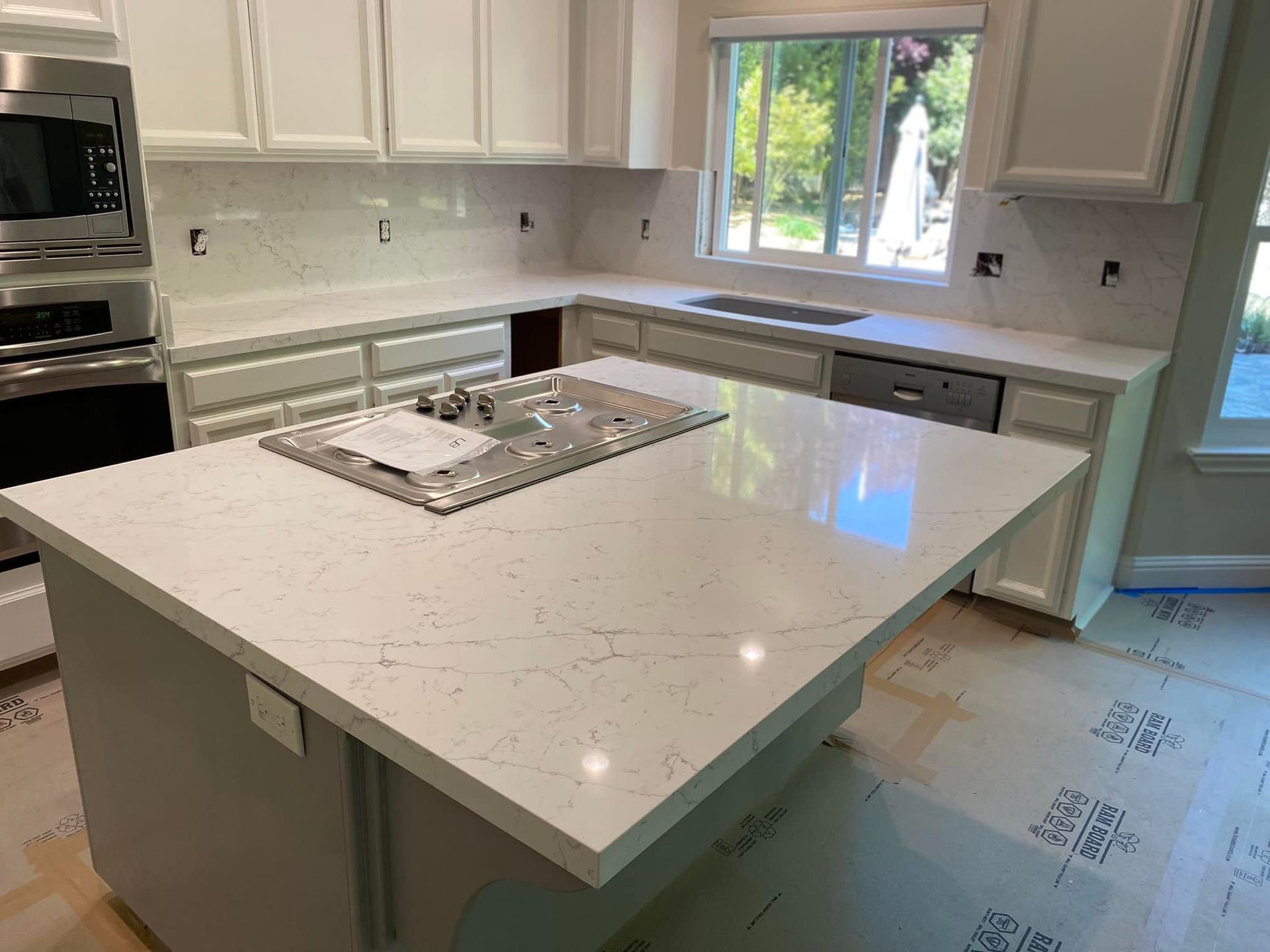 Newly renovated kitchen with white countertops, island, and cabinets.