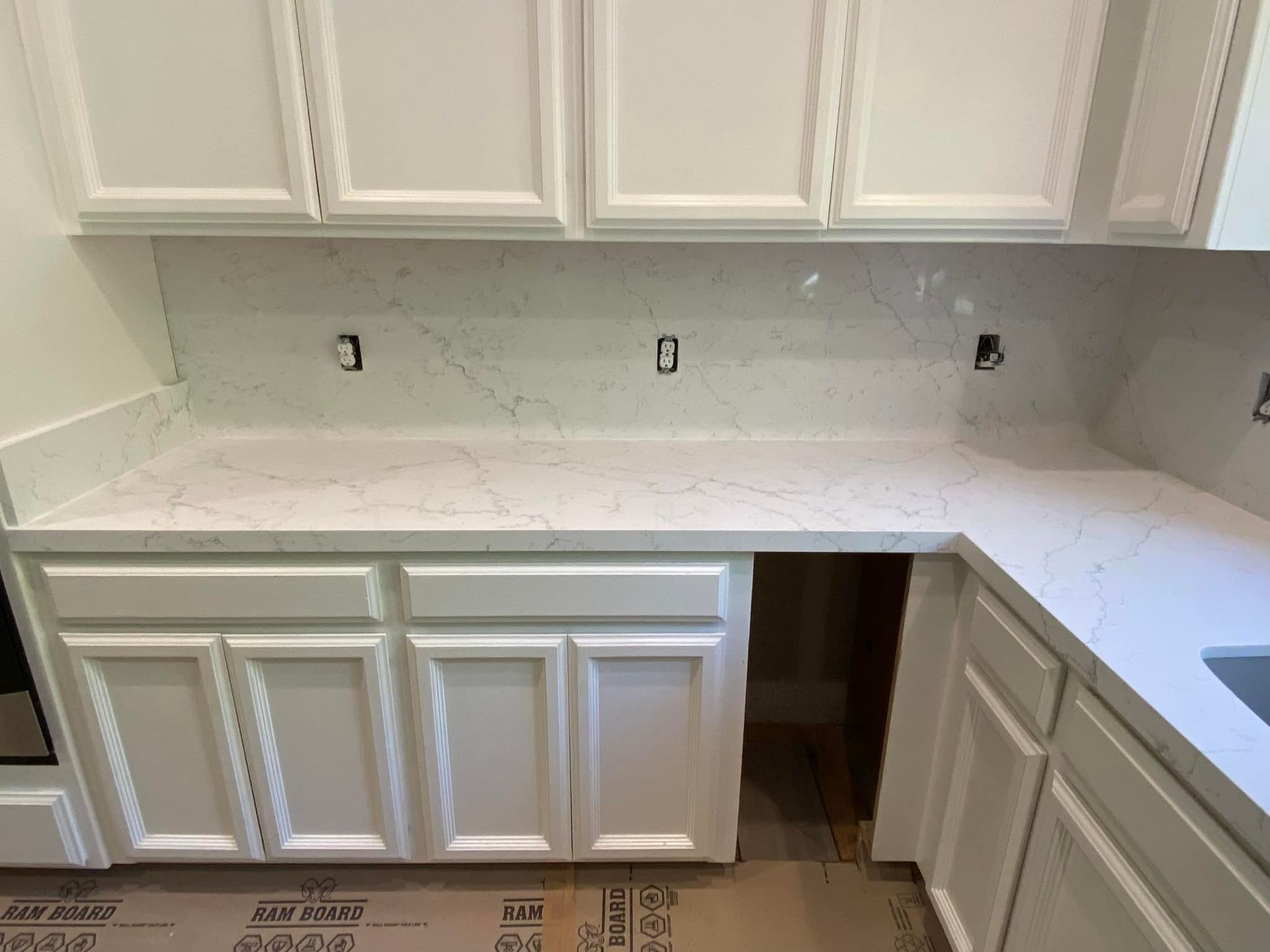 White kitchen cabinets with white quartz countertops and backsplash.