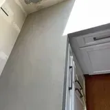 Gray wall section next to white kitchen cabinets with black handles, angled toward ceiling.