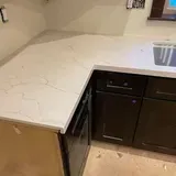 White quartz countertop with veining, dark cabinets, and a built-in oven in a kitchen.