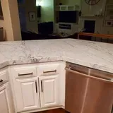 Kitchen island with white cabinets and granite countertop; stainless steel sink.
