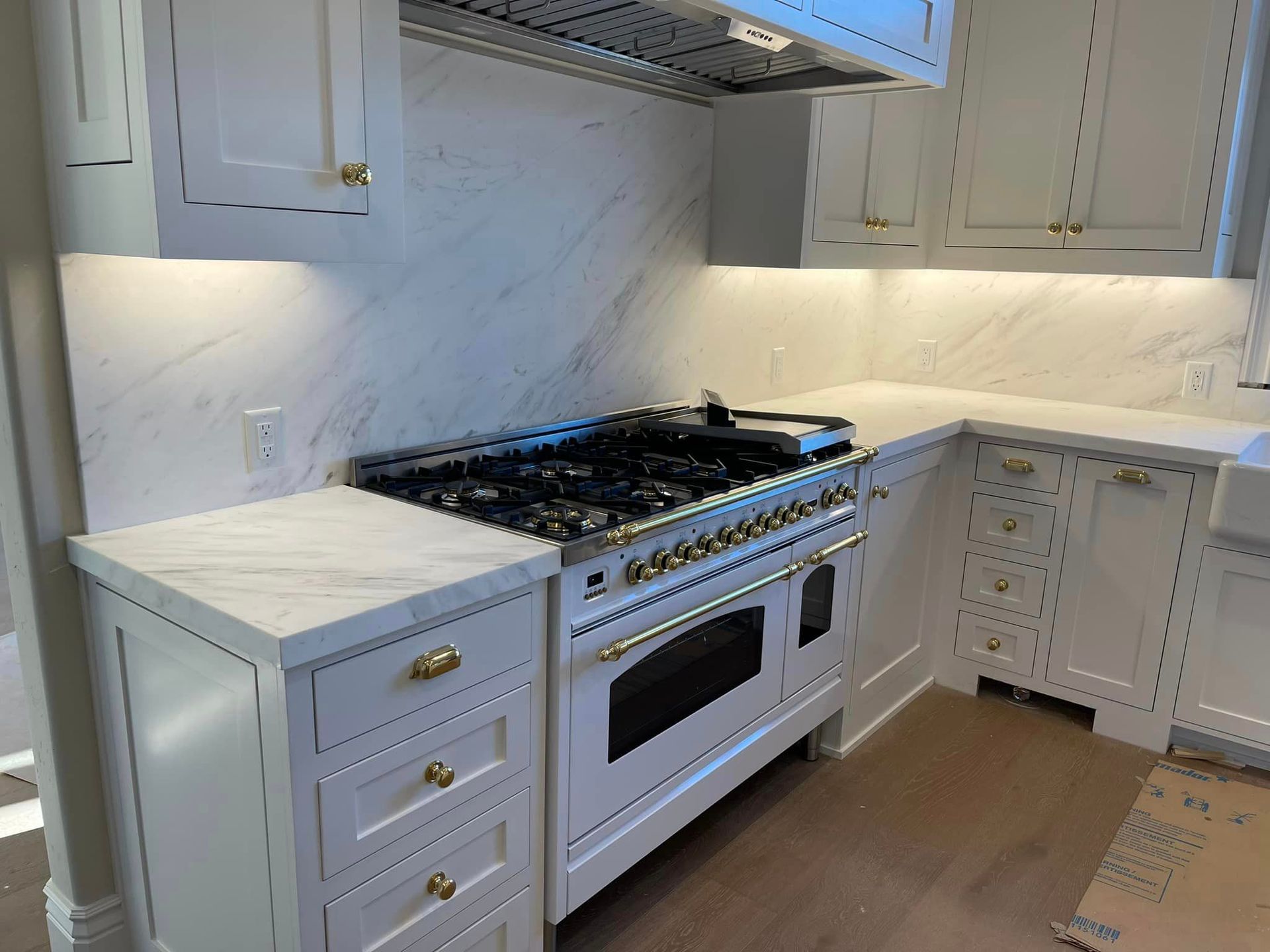 A kitchen with white cabinets and a stove top oven.