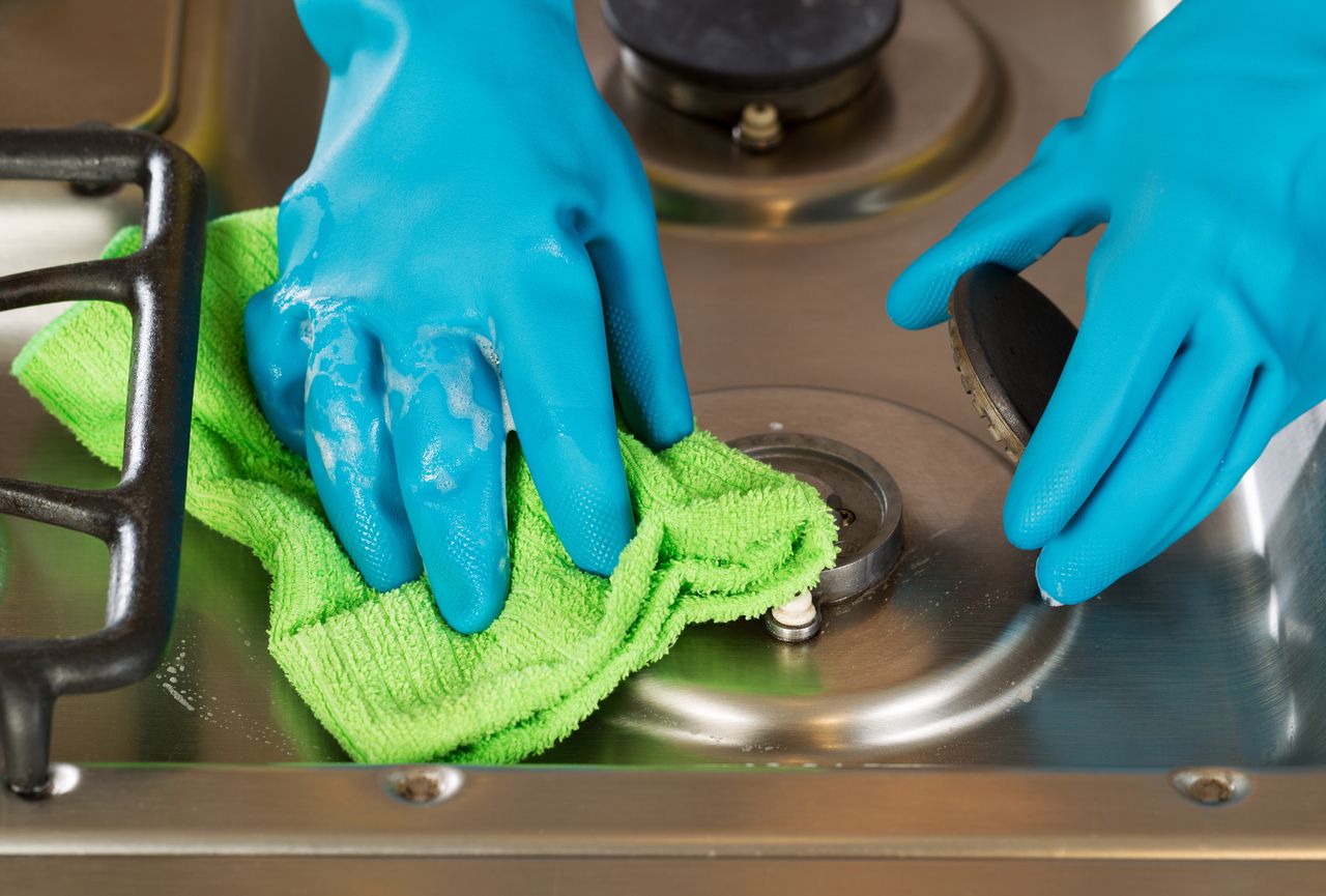 Hands polishing a stovetop.