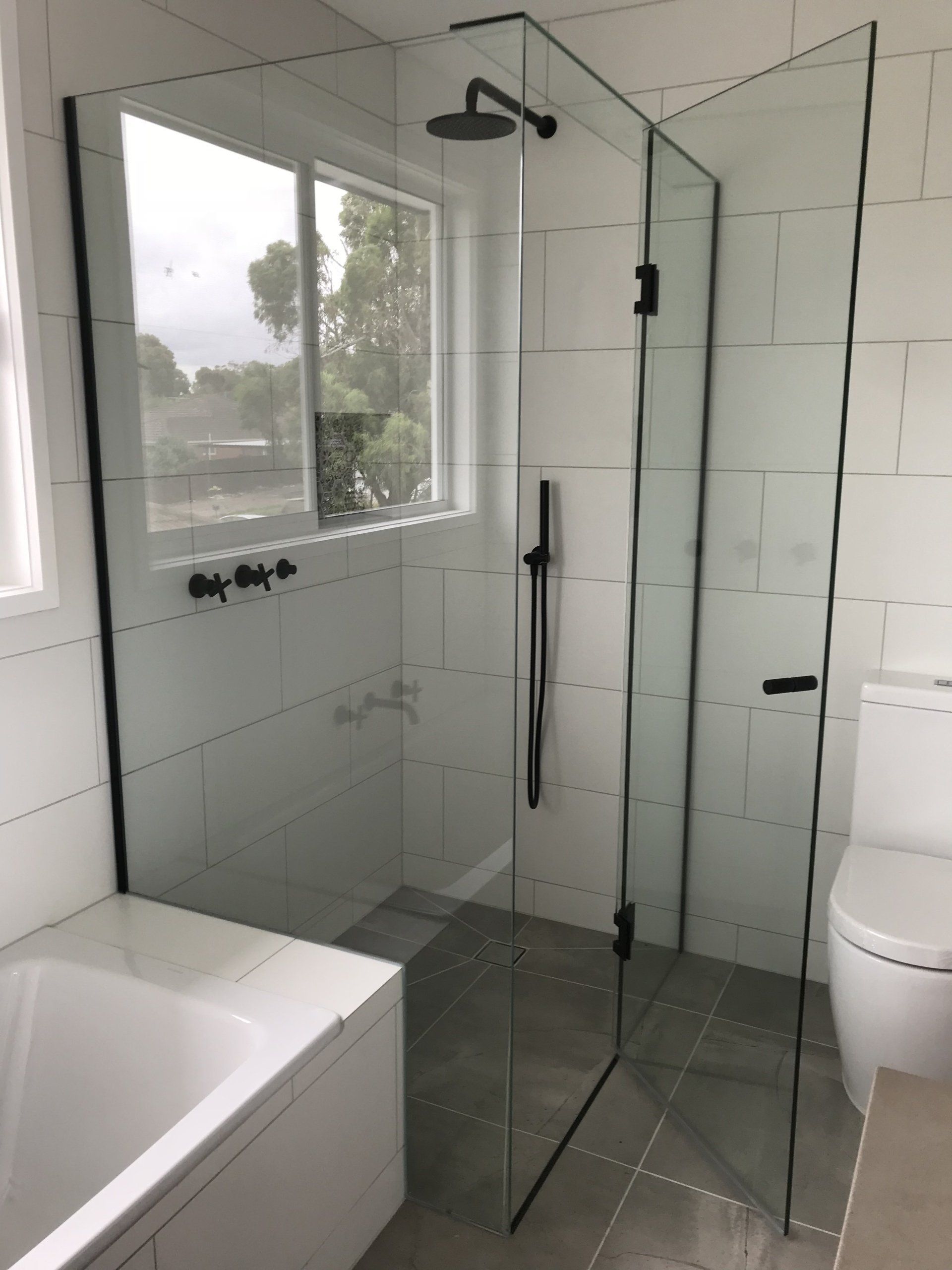 A bathroom with a bathtub , toilet , shower and window.