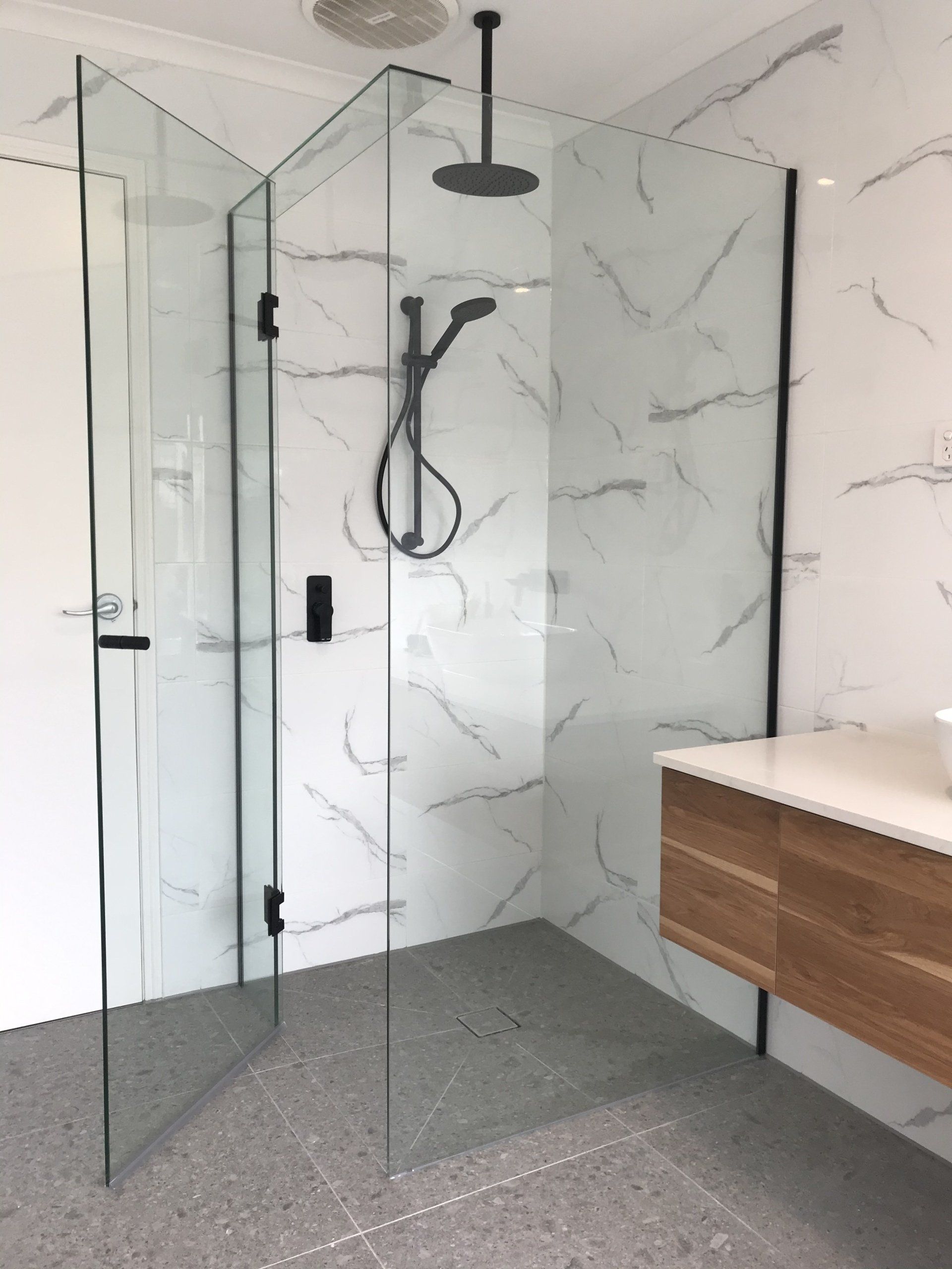 A bathroom with a walk in shower and a sink