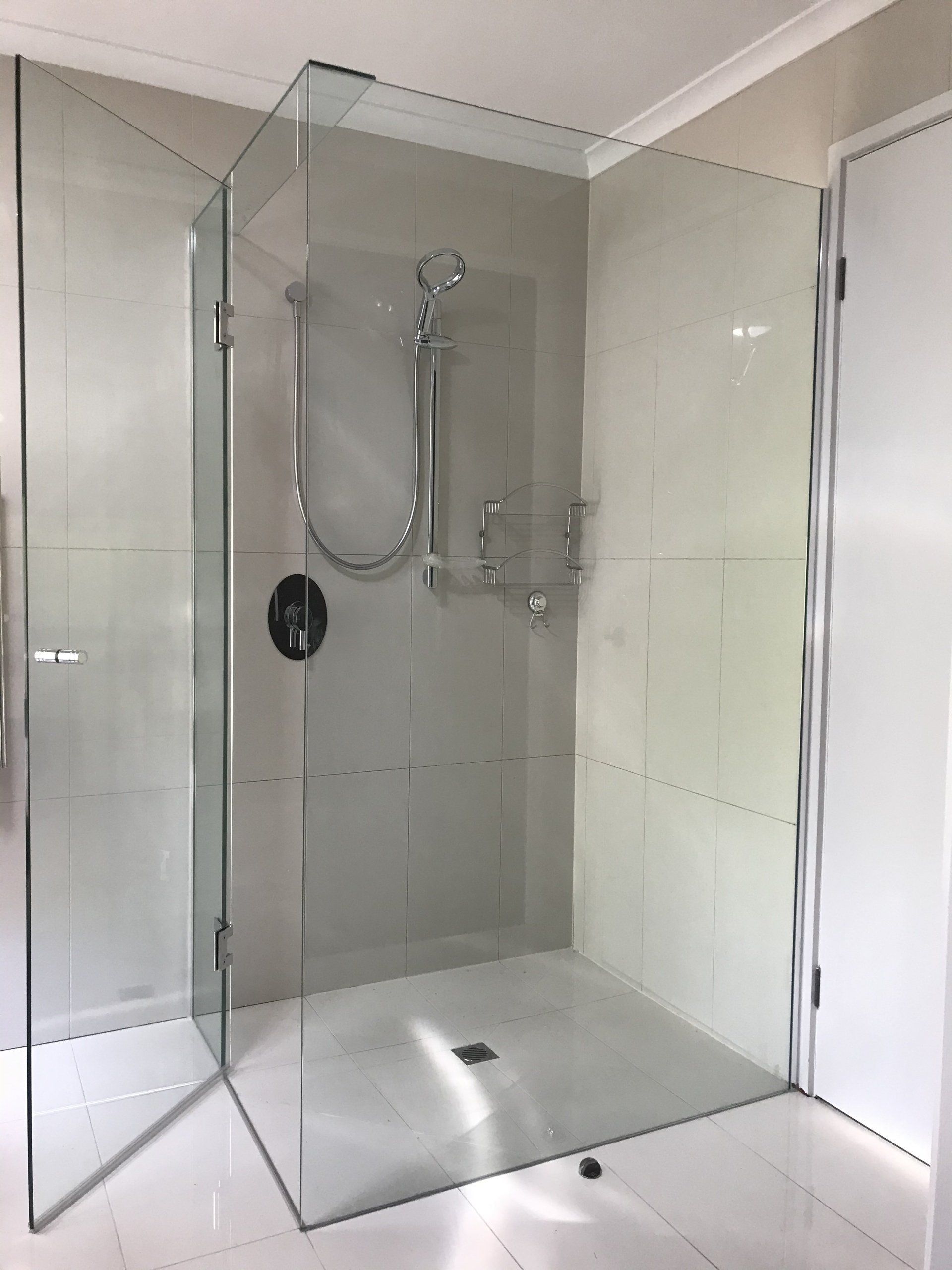 A bathroom with a walk in shower with a glass door.