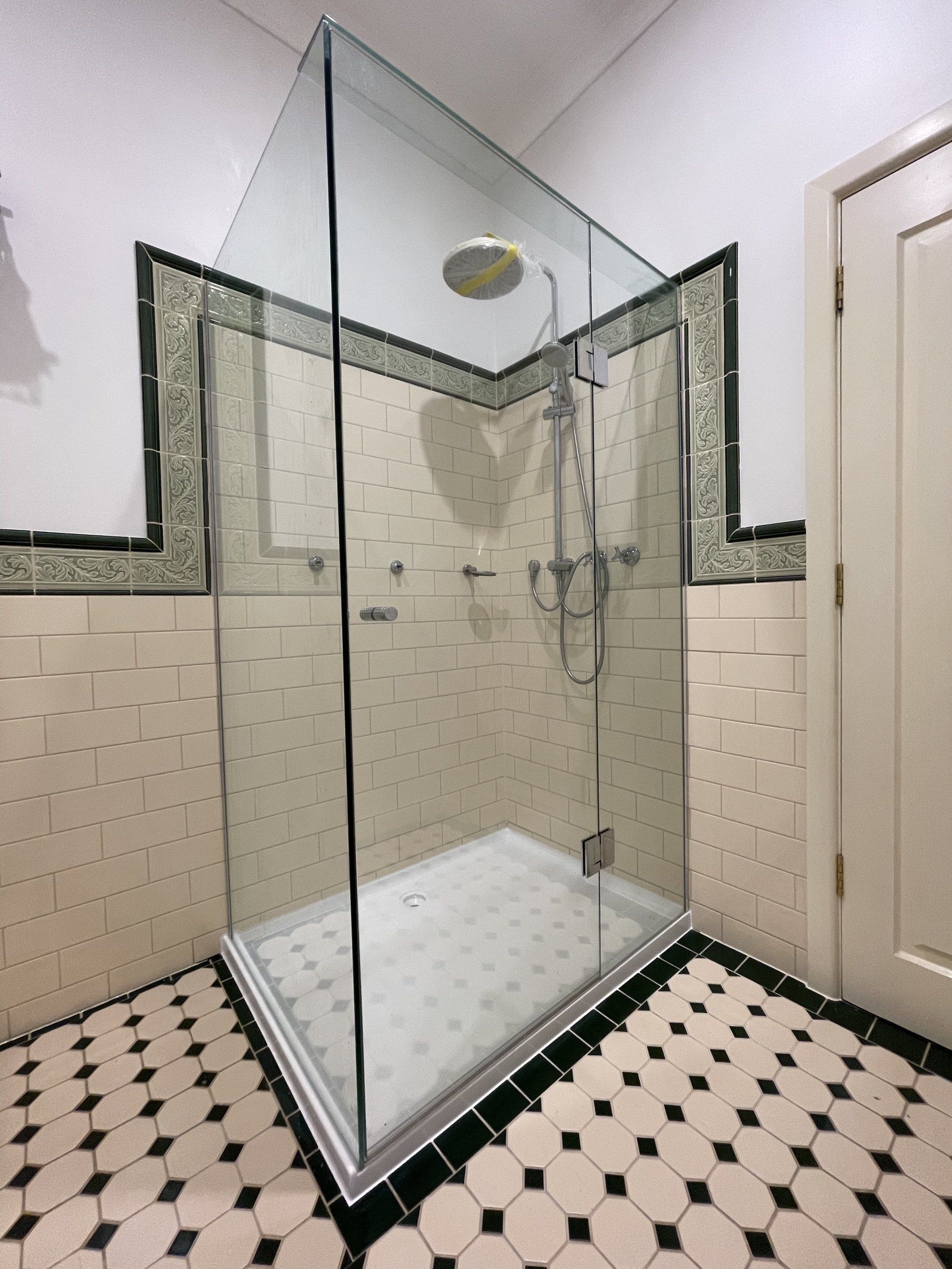 A bathroom with a walk in Frameless Hinged Shower Screen and a checkered floor
