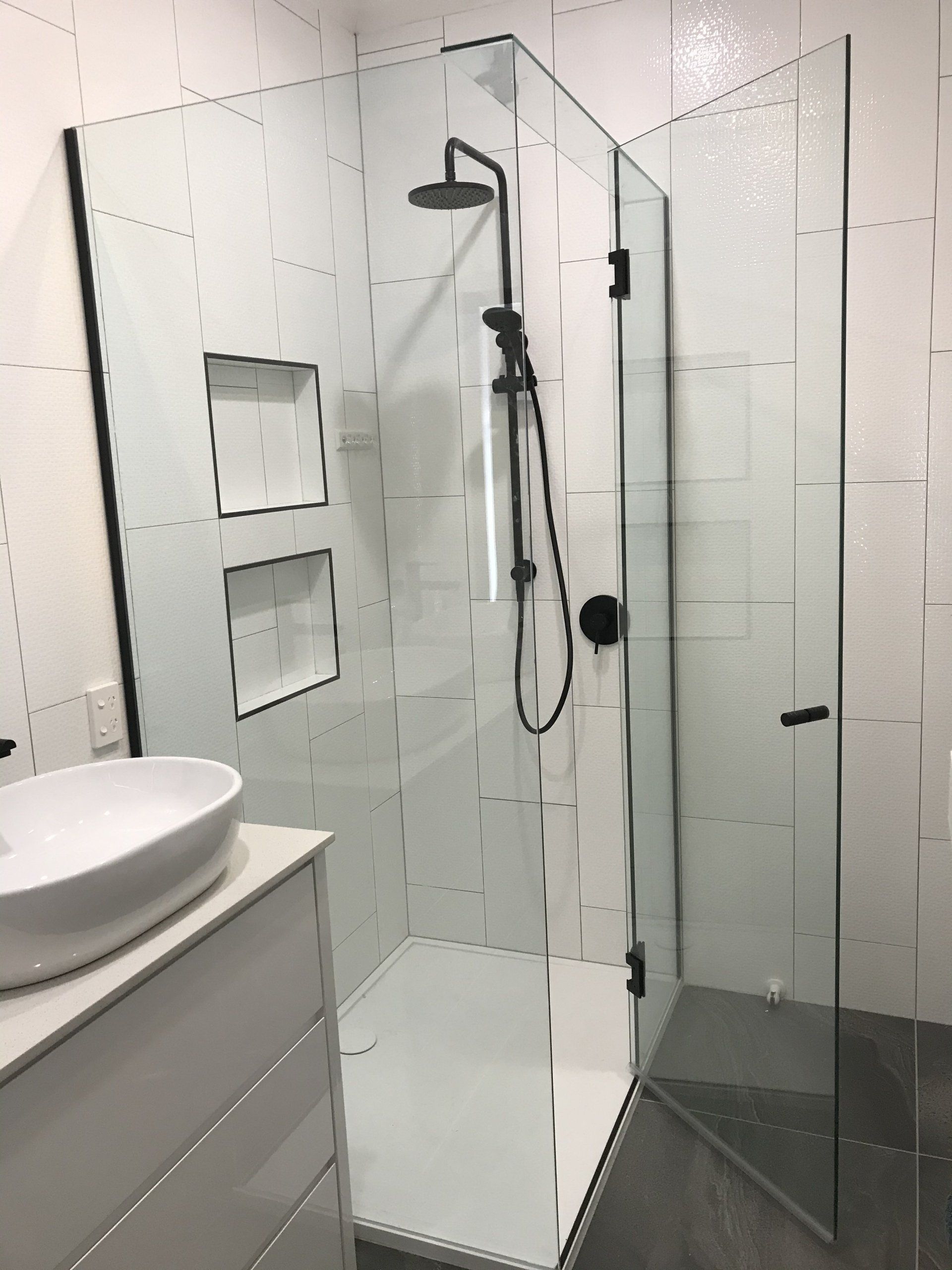 A bathroom with a walk in shower and a sink