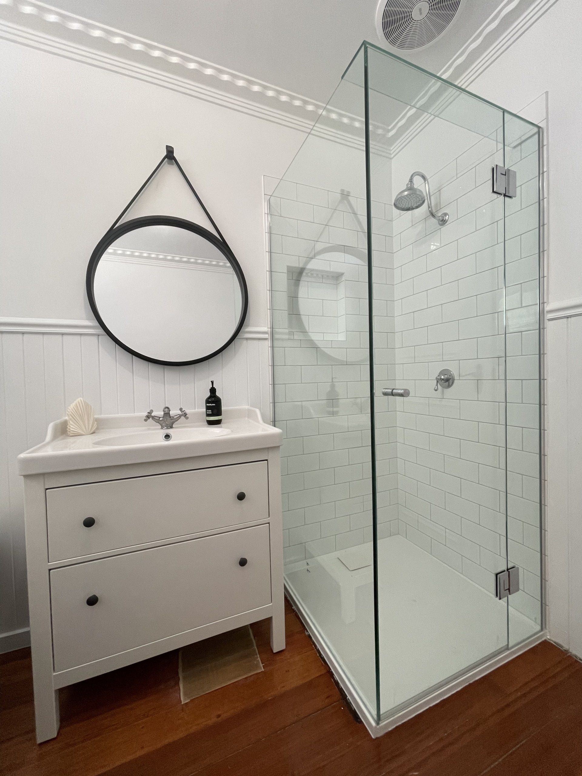 A bathroom with a sink a mirror and a walk in Frameless Hinged Shower Screen