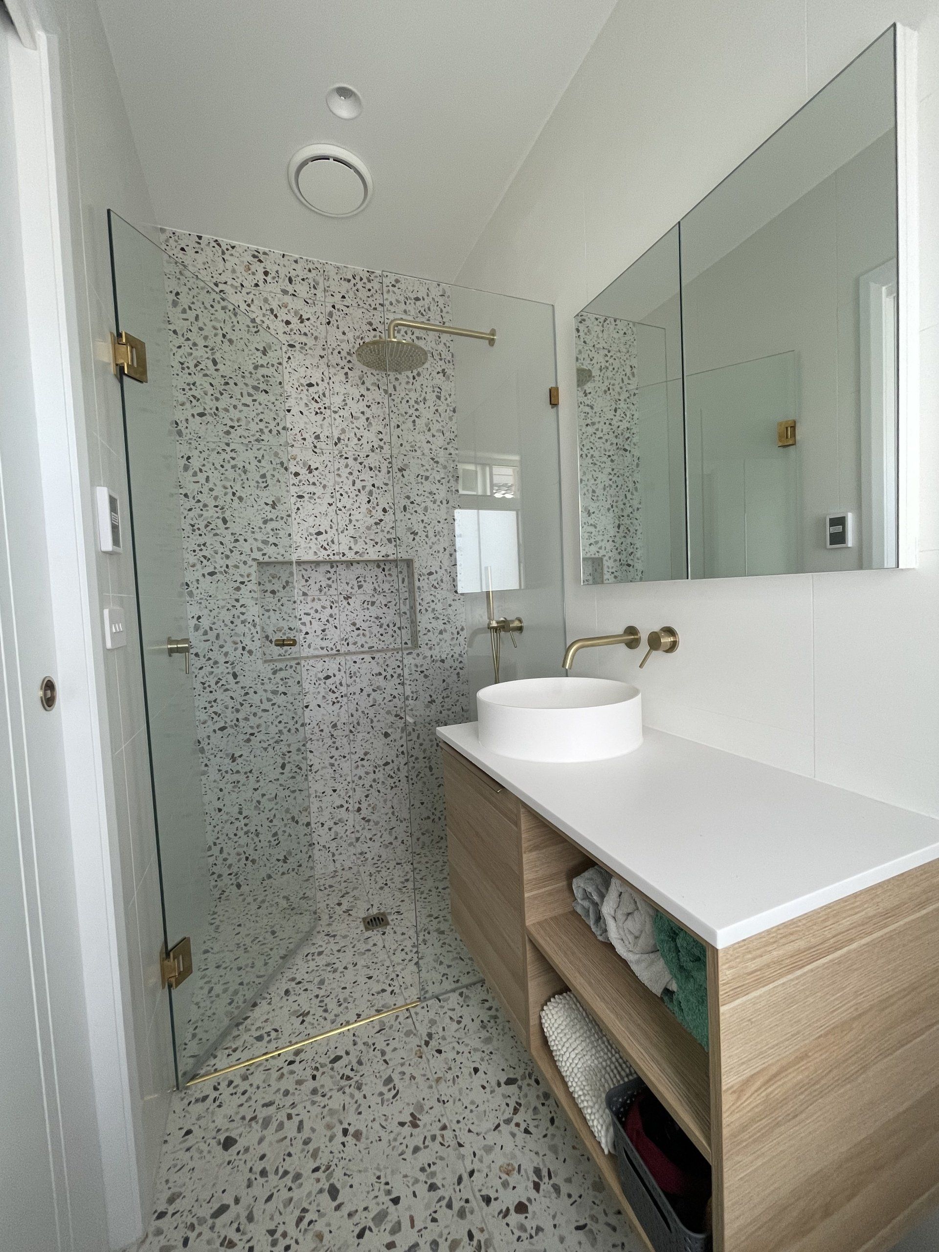 A bathroom with a sink , mirror and Frameless Hinged Shower Screen.