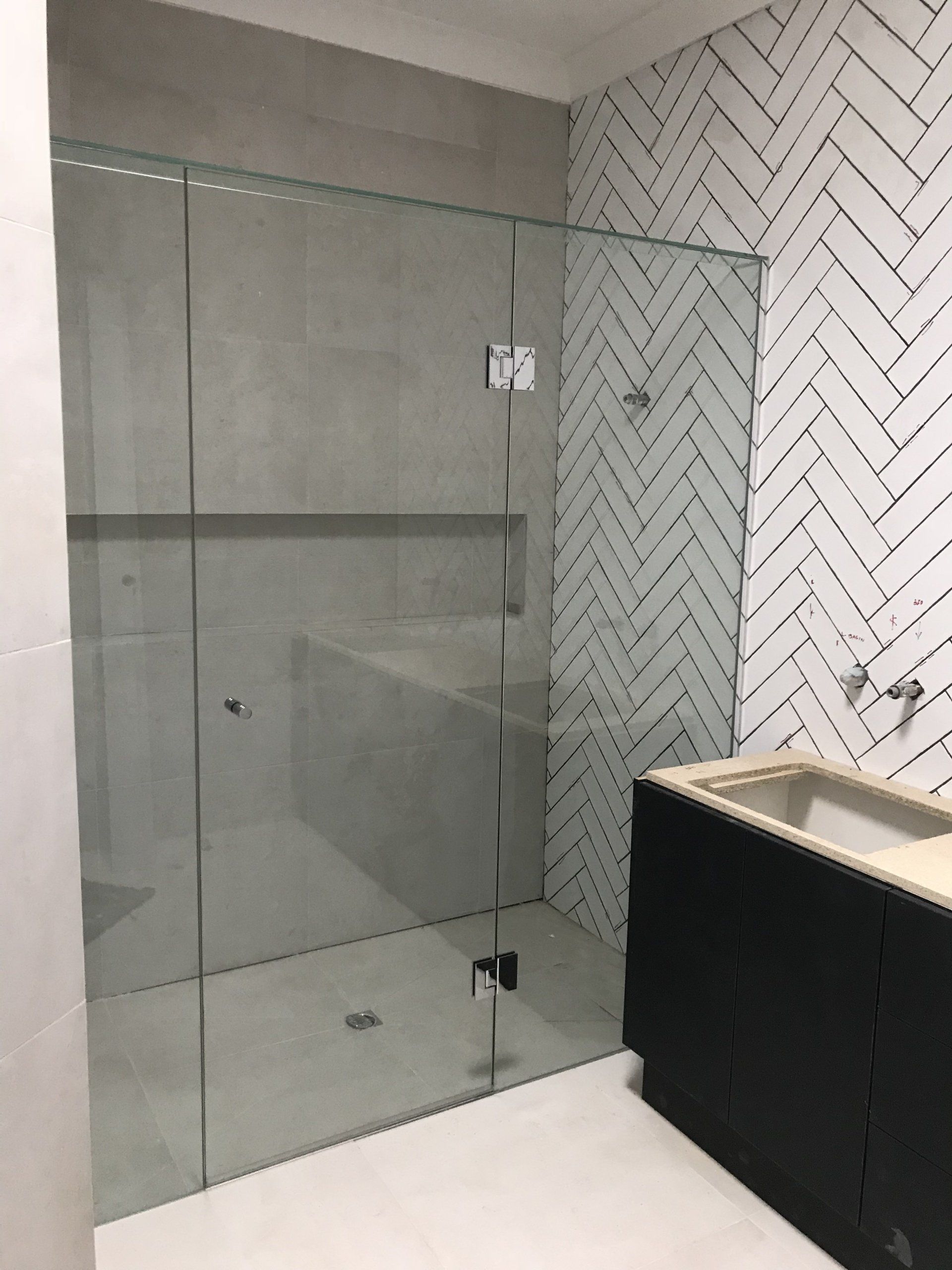 A bathroom with a walk in shower and a sink.