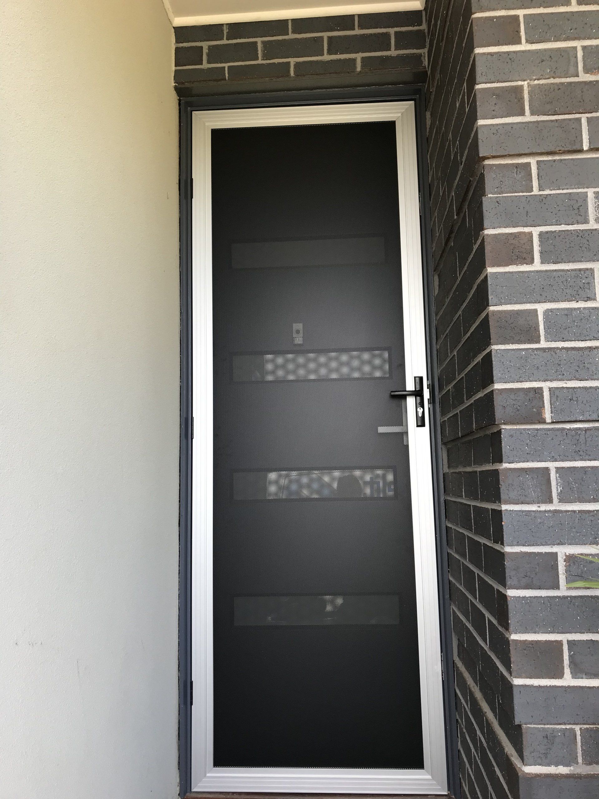 A black door with a white frame is sitting next to a brick wall.