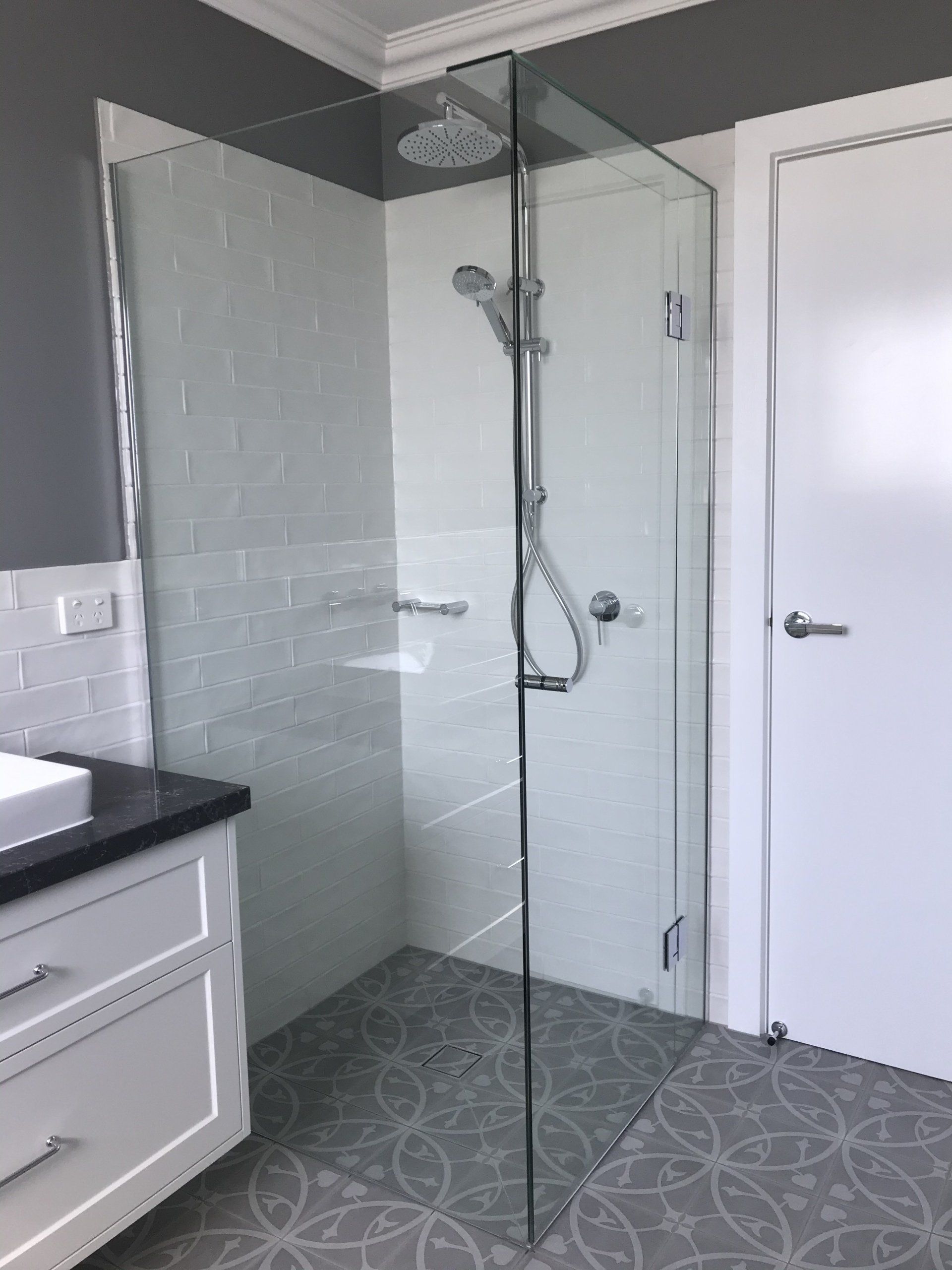 A bathroom with a walk in Frameless Hinged Shower Screen and a sink.