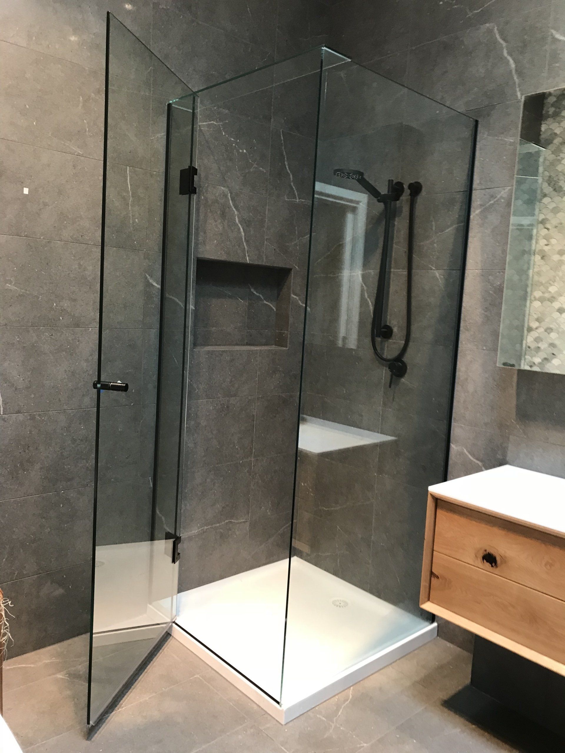A bathroom with a walk in shower and a wooden vanity.