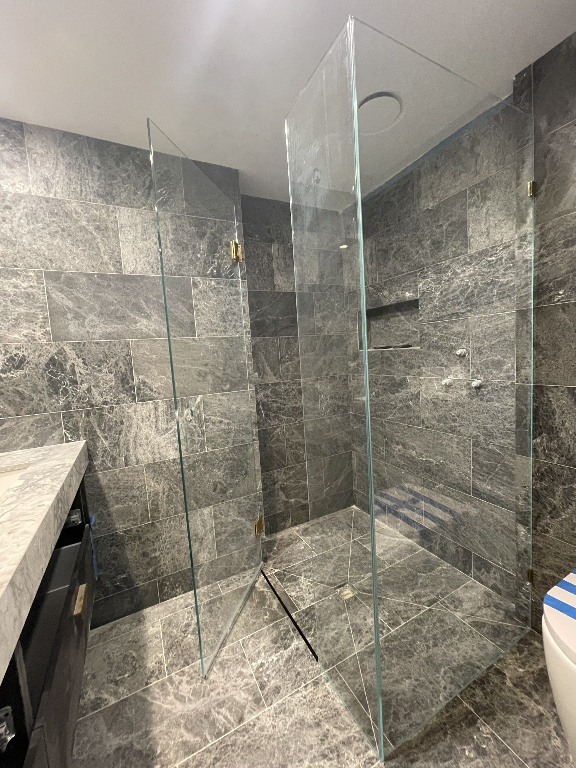 A bathroom with a walk in Frameless Hinged Shower Screen and a toilet.