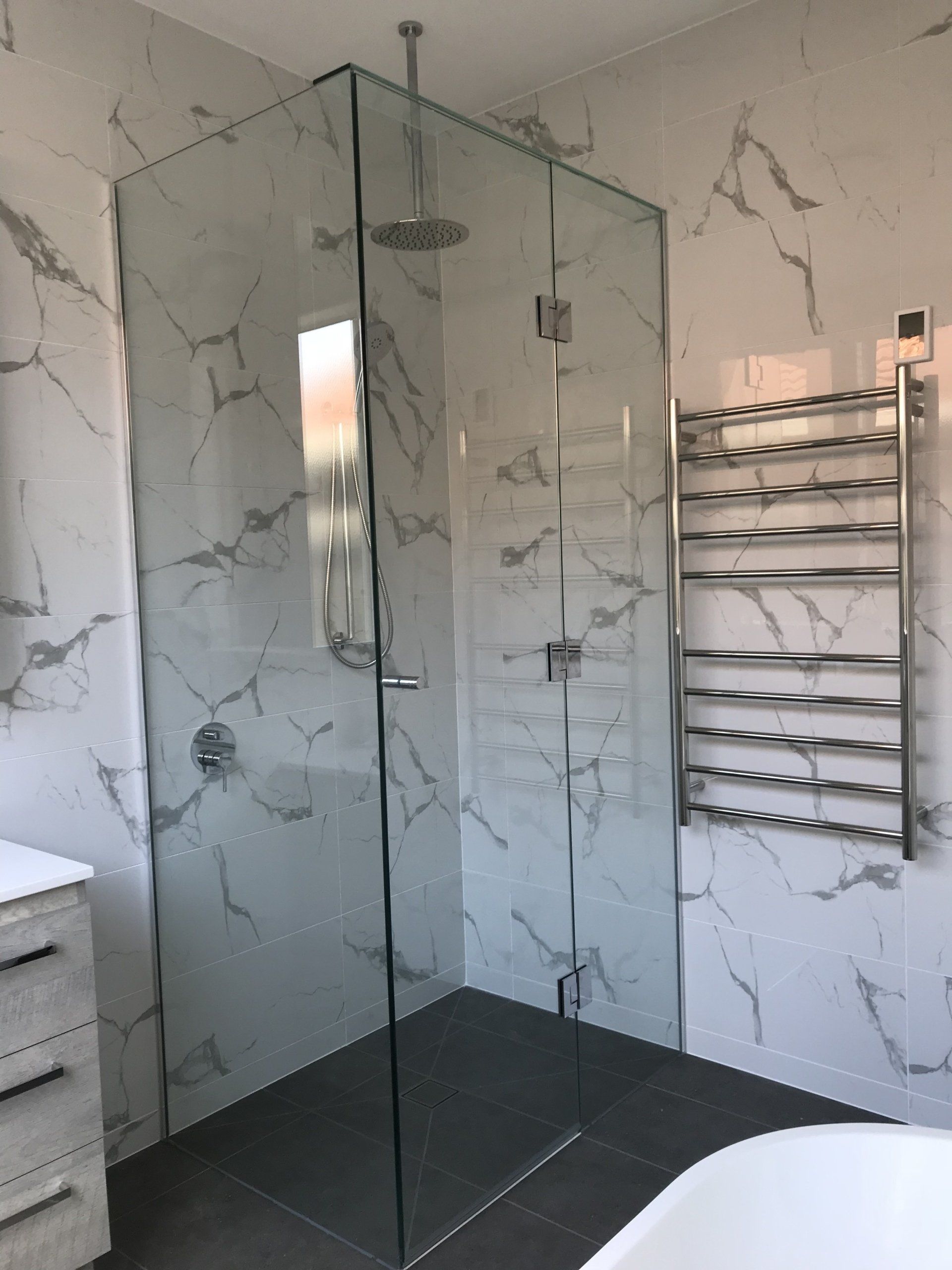 A bathroom with marble walls and a walk in shower.