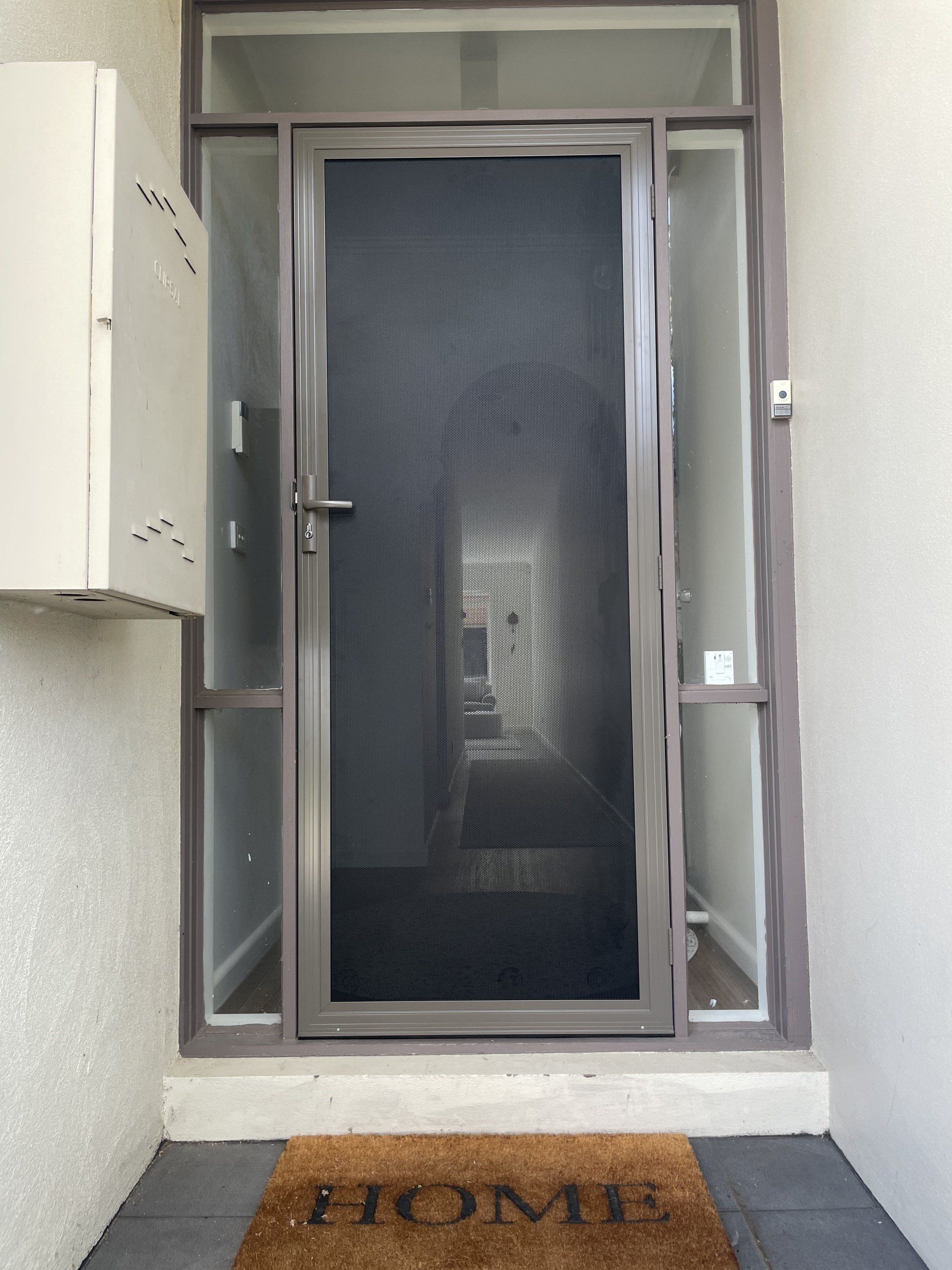 A Security Door with a screen and a welcome mat that says home