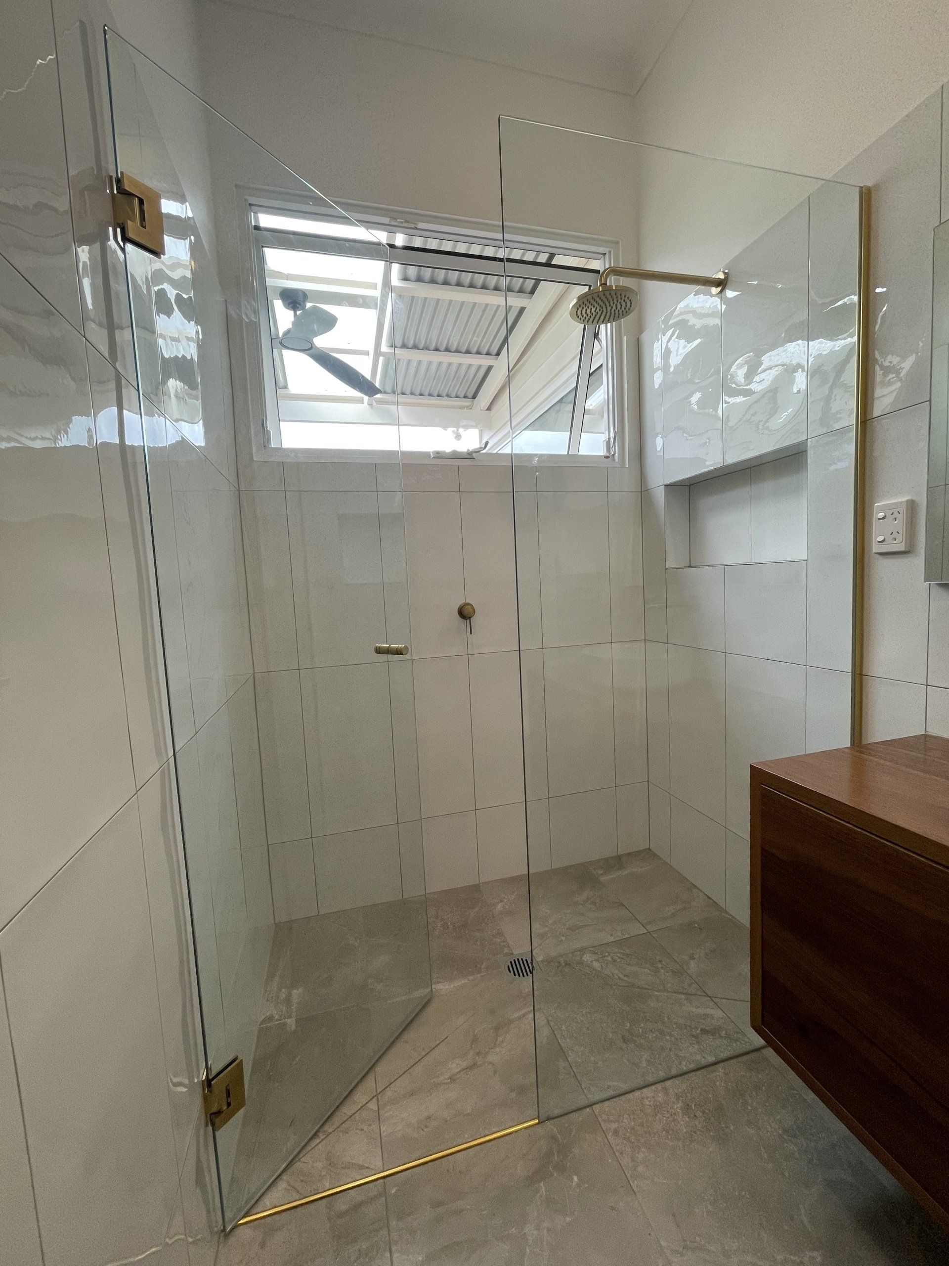 A bathroom with a walk in shower and a wooden vanity.