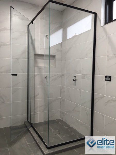 A shower stall with a black frame and clear glass
