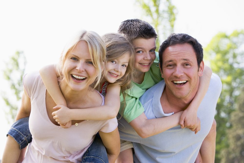 Family Smiling, With Parents Giving Piggyback Rides Outdoors — Amanda Jade Photography In Gordonvale, QLD