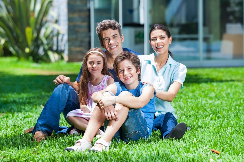 Family of Four Sitting on Grass, Smiling. Backyard Setting, Sunny Day — Amanda Jade Photography In Gordonvale, QLD