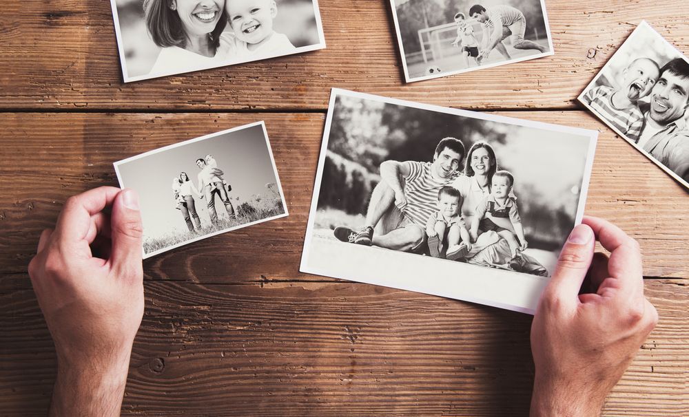 Hands Holding Family Photo, More Photos on Wooden Table — Amanda Jade Photography In Gordonvale, QLD