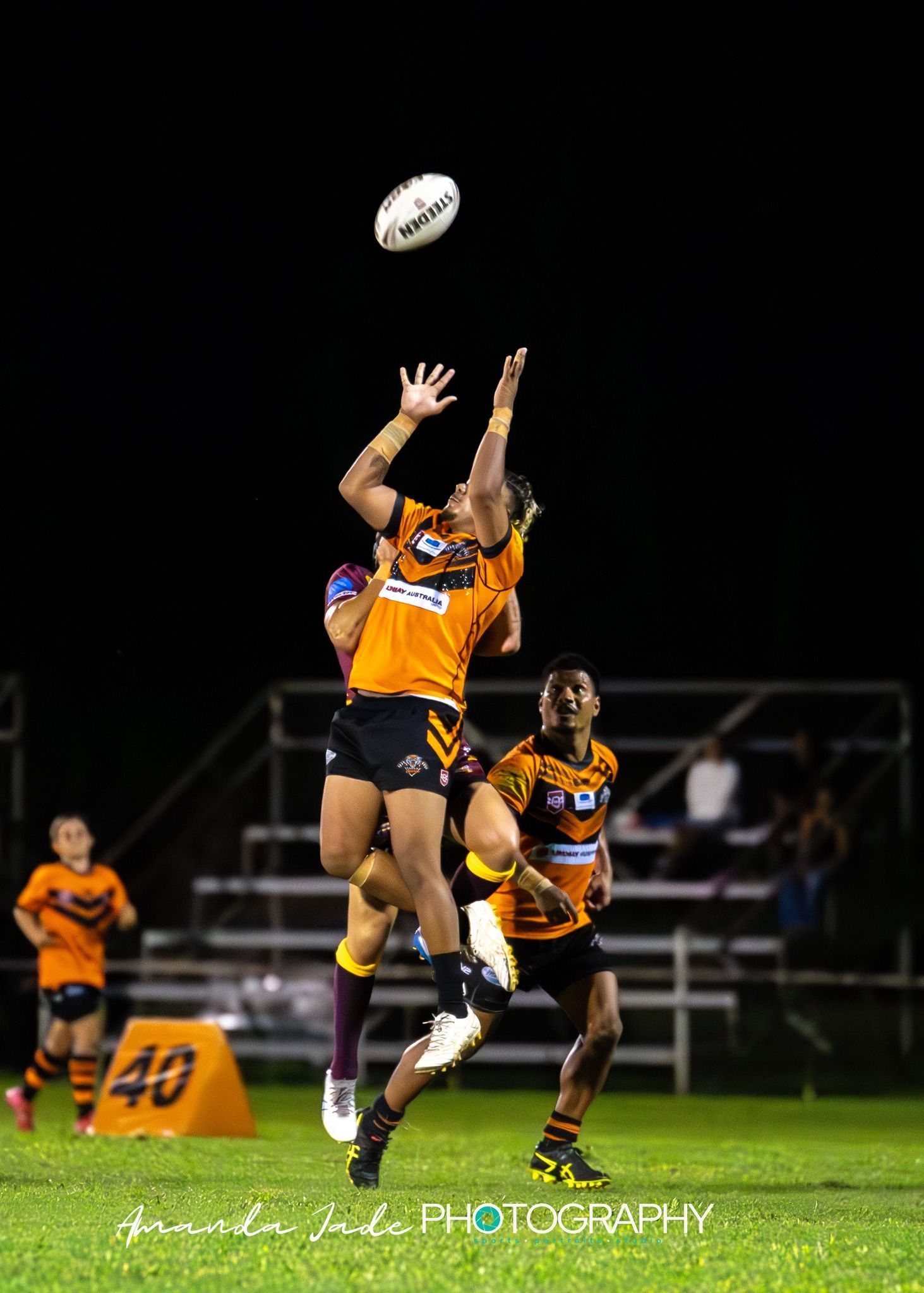 Rugby Players Jumping For A Ball During A Night Game — Amanda Jade Photography In Gordonvale, QLD