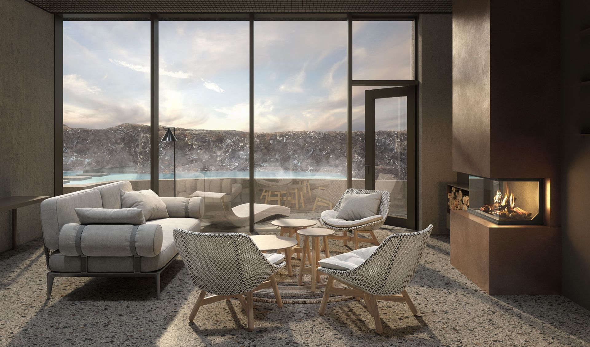 Living room with snowy landscape view. Gray sofa, wicker chairs, fireplace, and large windows.