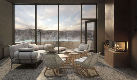 Living room with snowy landscape view. Gray sofa, wicker chairs, fireplace, and large windows.