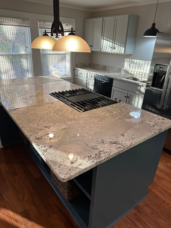A kitchen with white cabinets, granite countertops, stainless steel appliances.