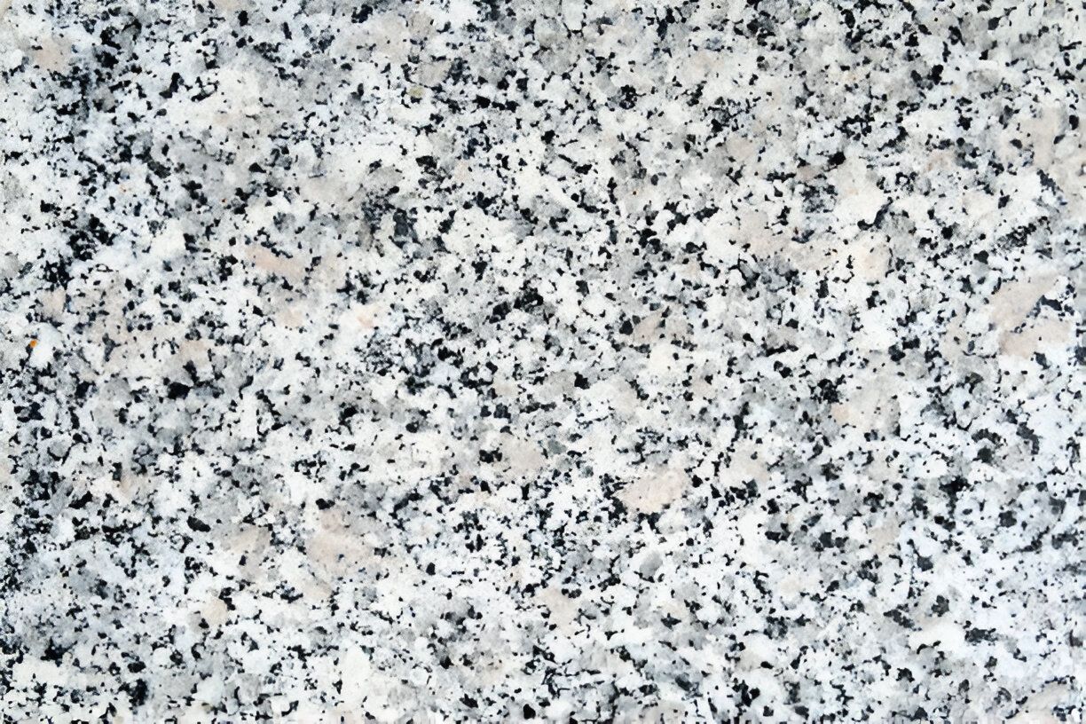 A close up of a white granite counter top with black spots. A close up of a white granite counter top with black spots.