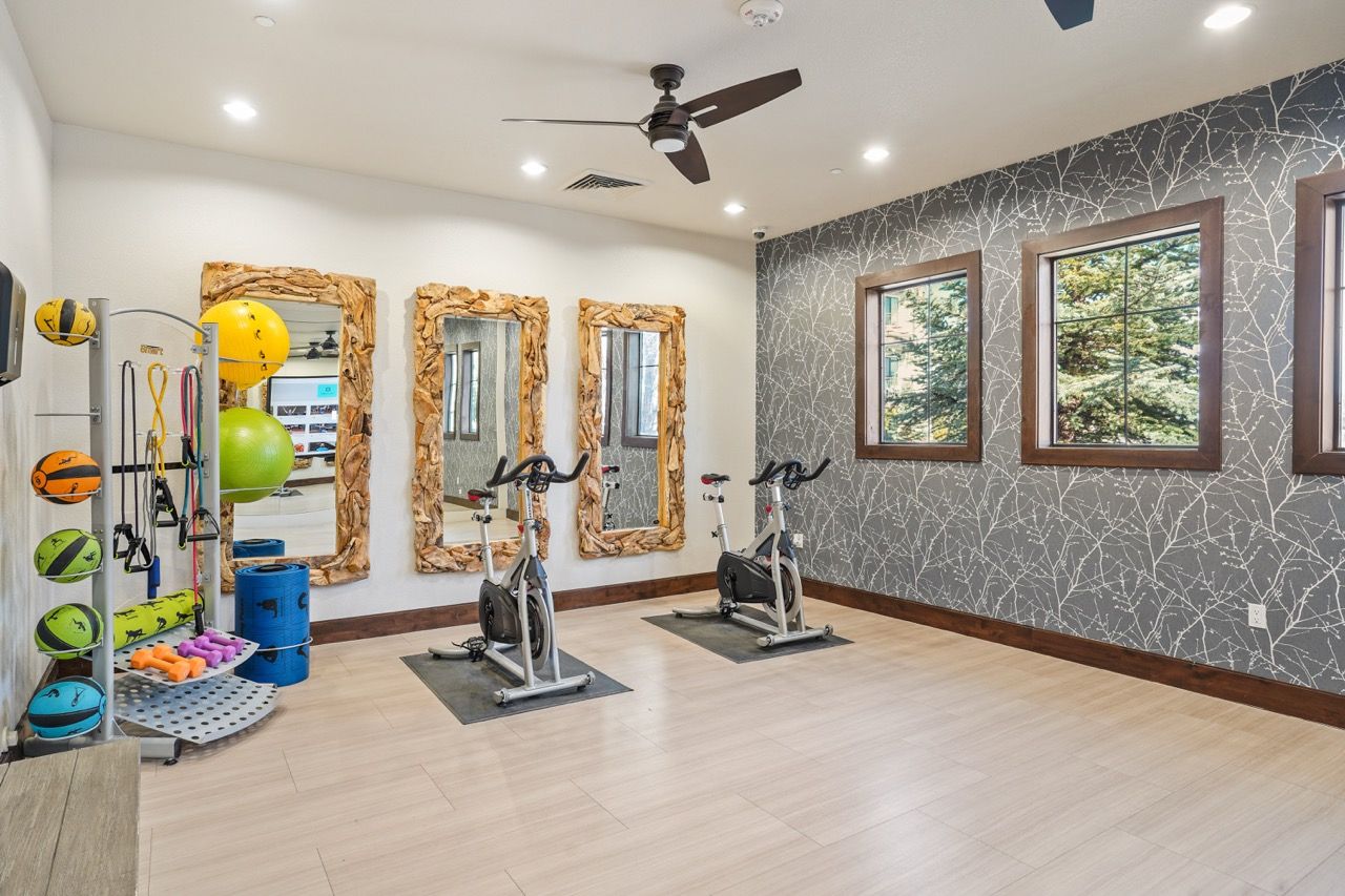 Indoor community gym with stationary bikes, weights, and mirrors.