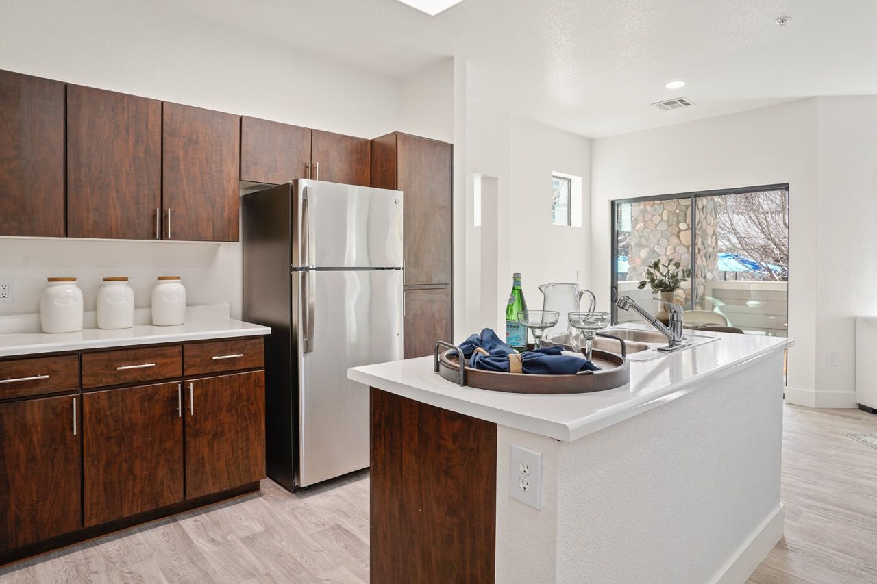 Modern kitchen with dark wood cabinets, stainless steel refrigerator, and a white island.