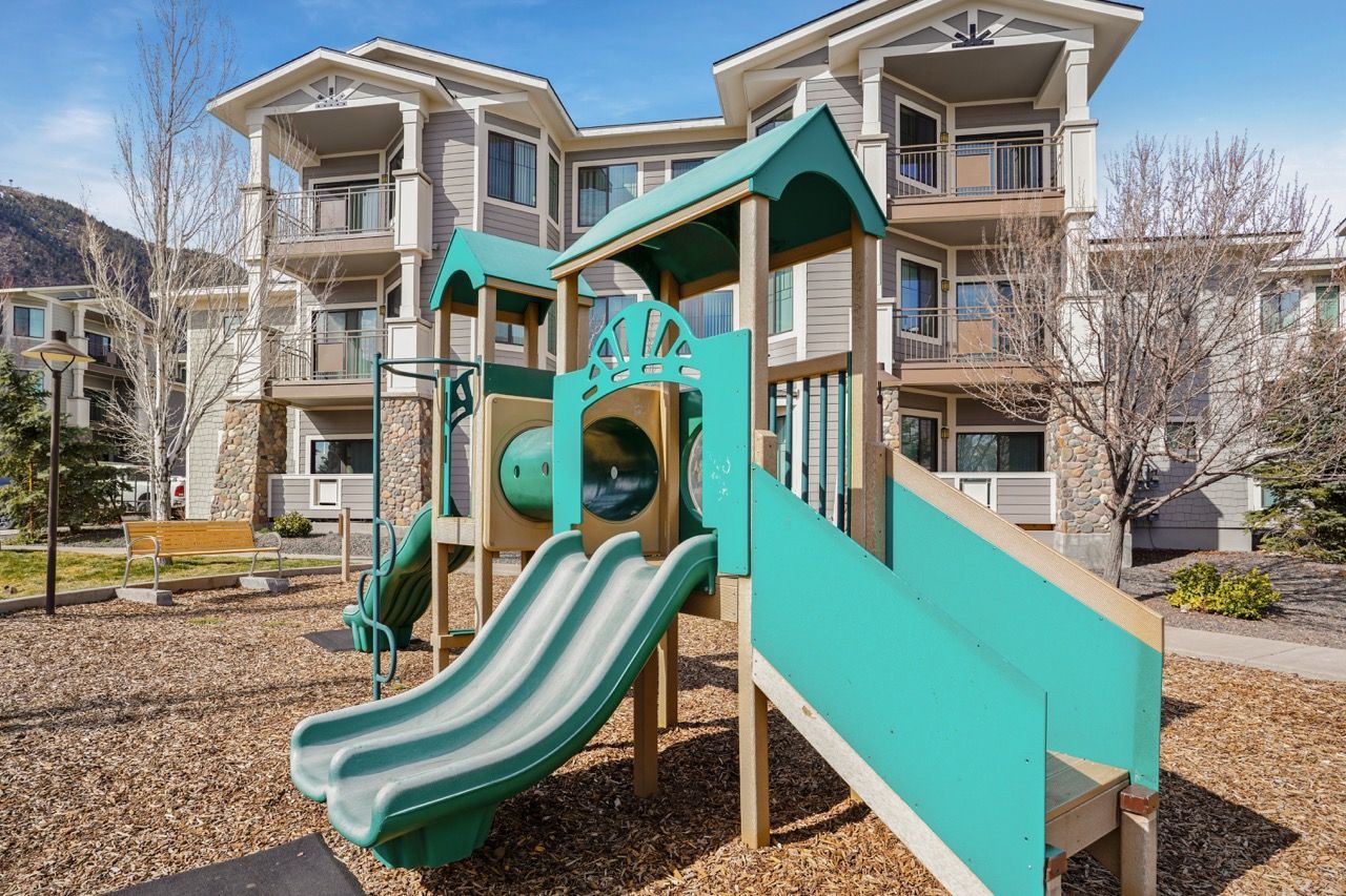 Teal and beige children's playground with slides in a residential apartment courtyard.
