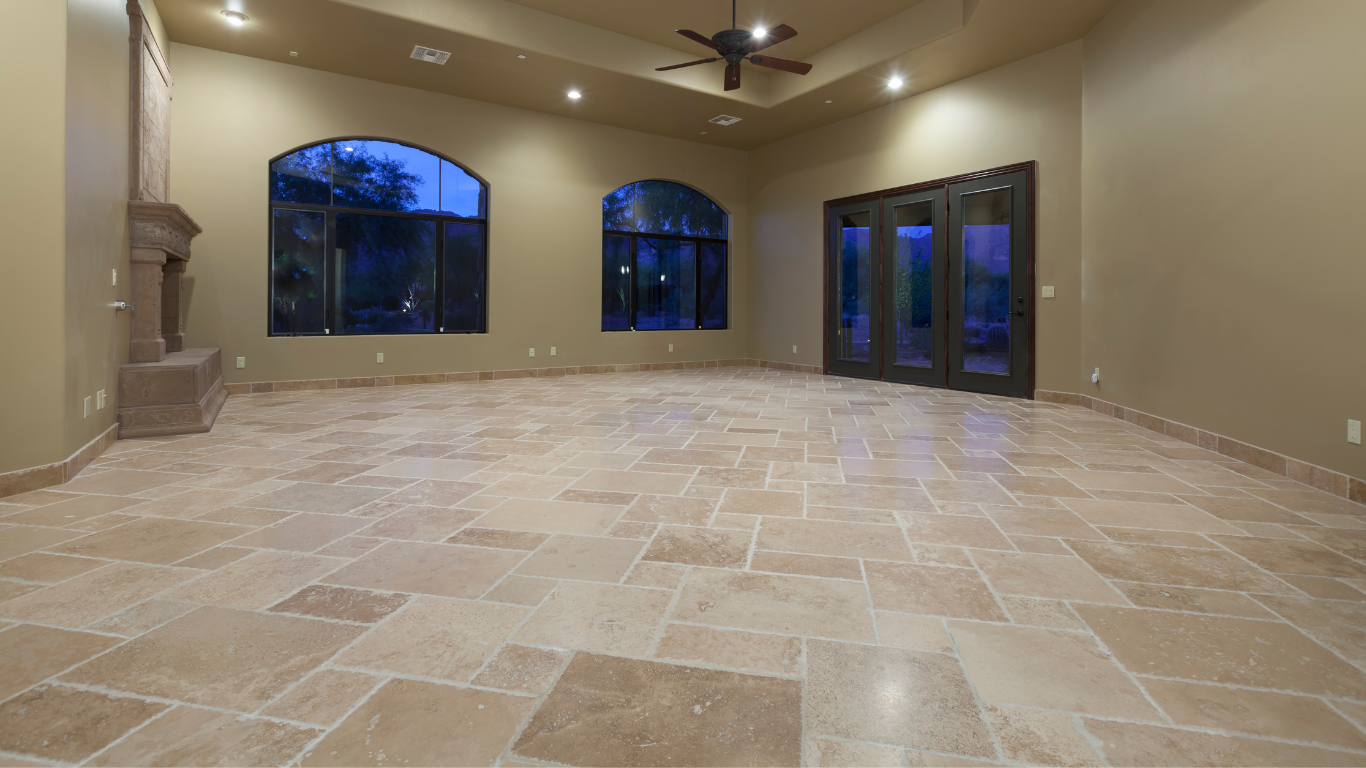 Empty living room with tan tile floor, arched windows, and fireplace.