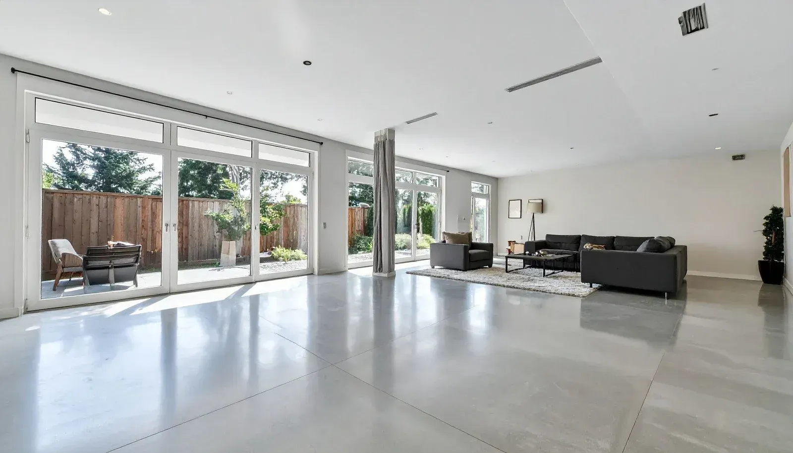 Modern white kitchen with island, stainless steel appliances, and large windows.