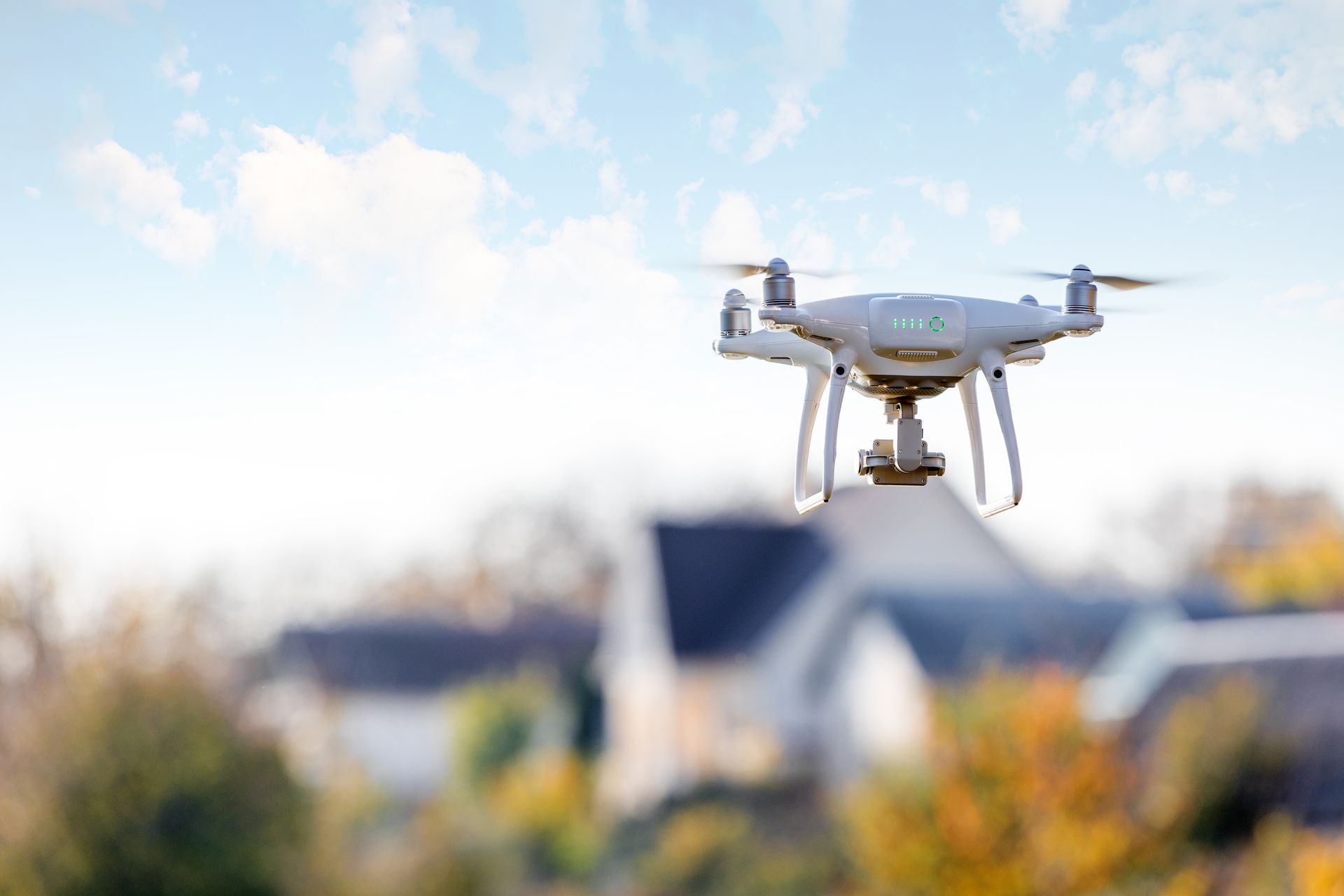 Drone hovering near houses against a cloudy sky.