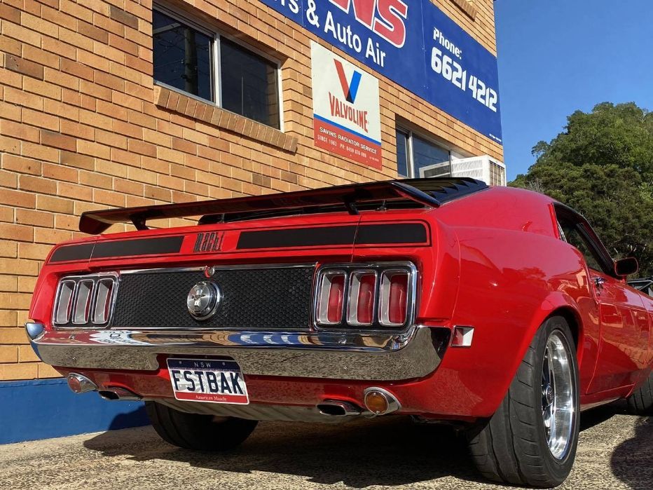 A Red Mustang is Parked in Front of a Brick Building — Savins Radiator Service In Lismore, NSW