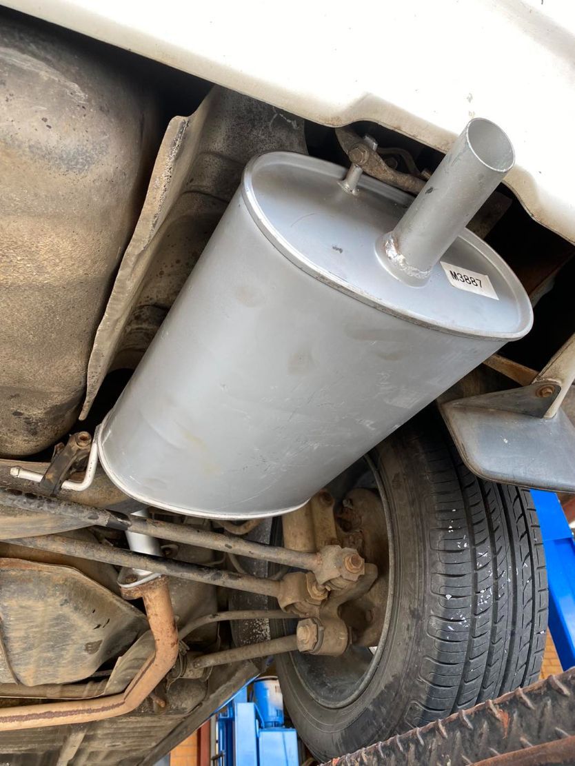 A Exhaust Pipe is Hanging From the Underside of a Car — Savins Radiator Service In Lismore, NSW