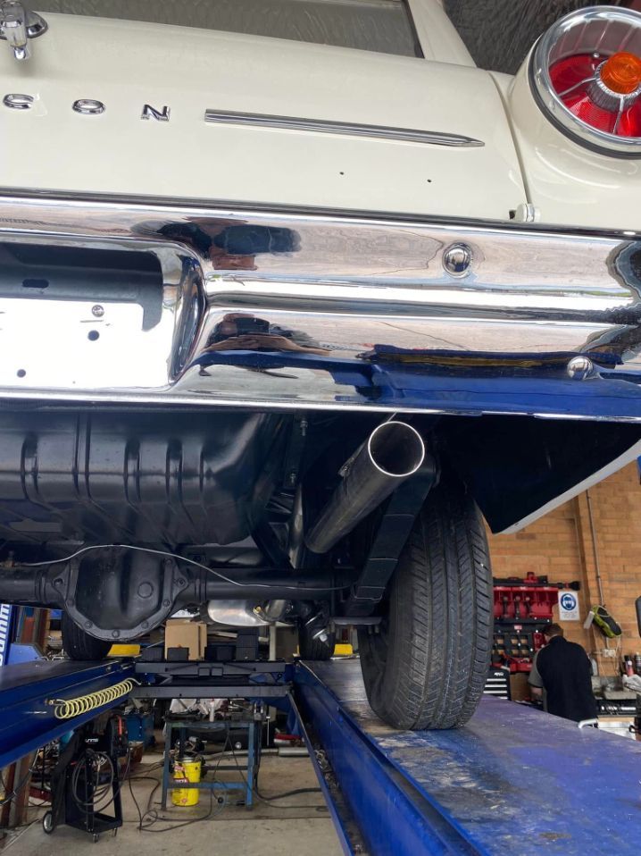 A White Car is Sitting on a Lift in a Garage — Savins Radiator Service In Lismore, NSW