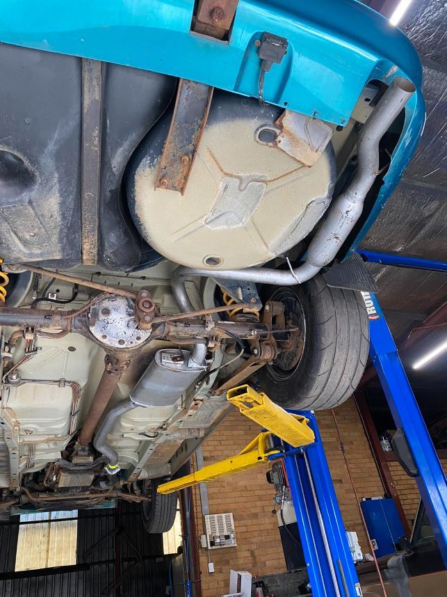 A Blue Car is Sitting on a Lift in a Garage — Savins Radiator Service In Northern Rivers, NSW