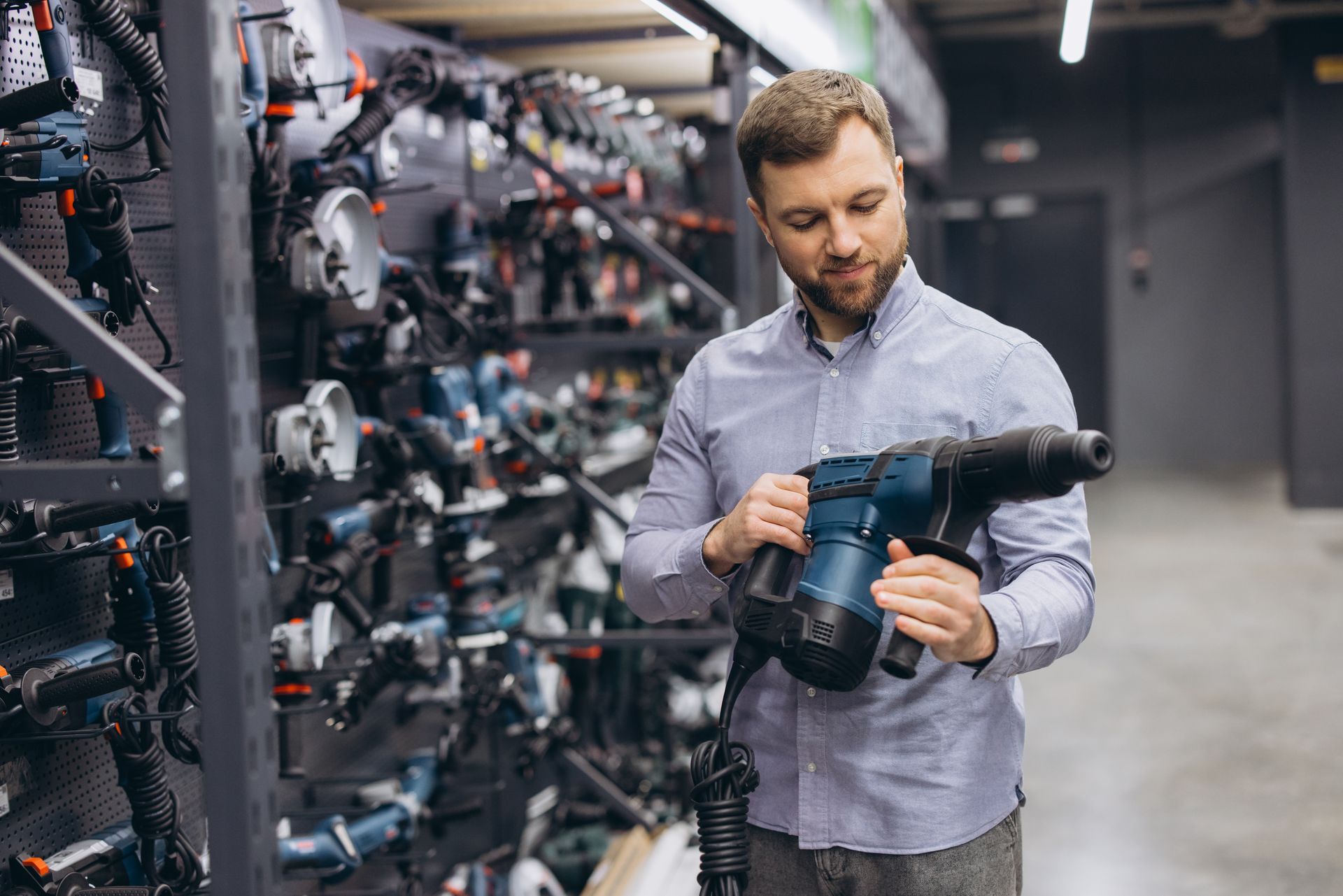 A man shopping for power tools in a hardware store, selecting a hammer drill.