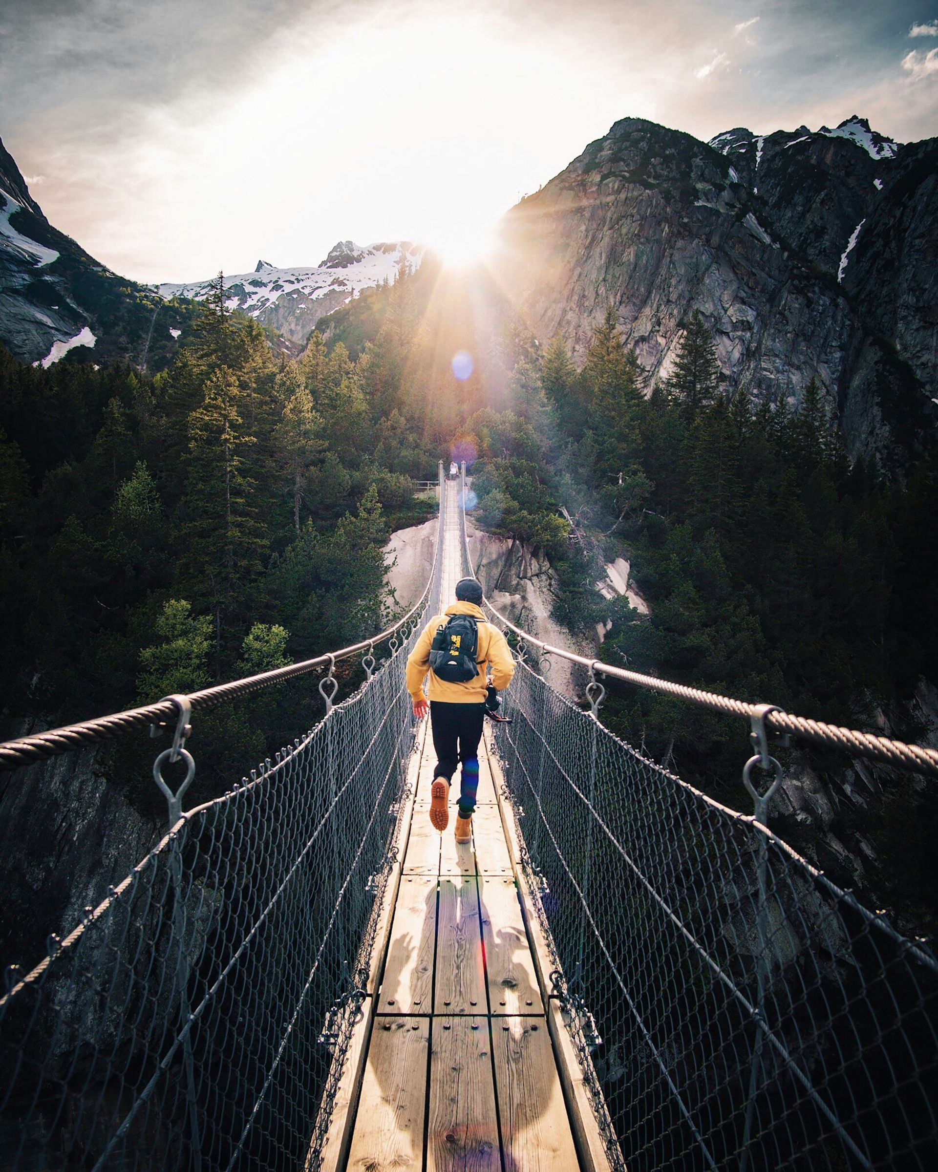 a man running on a bridge towards the sun with beautiful nature scenery in the back