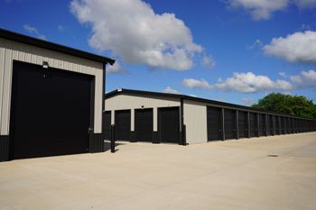 Row of black storage units with white trim under a blue sky with clouds Row of black storage units with white trim under a blue sky with clouds