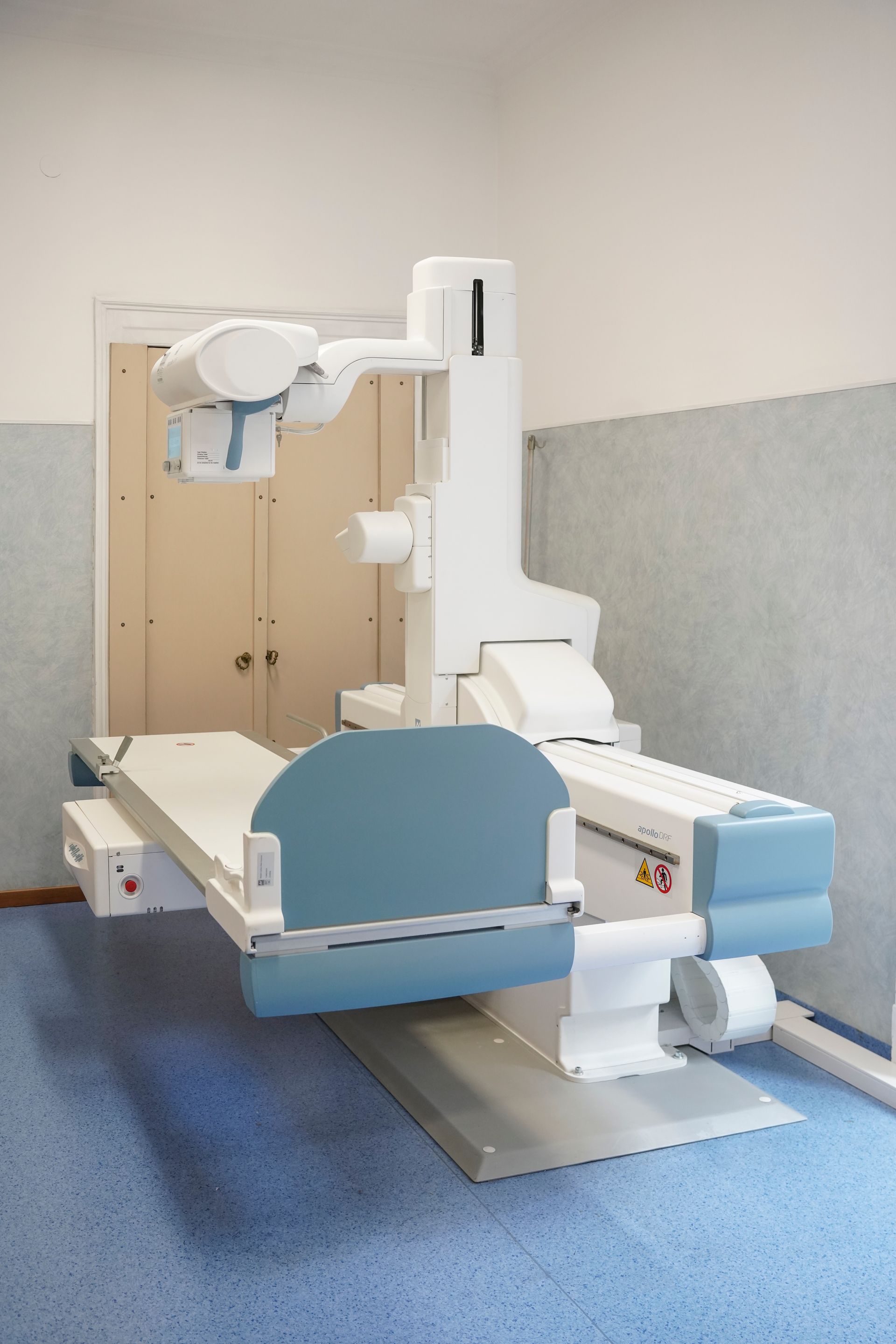 In una stanza con il pavimento blu c'è una macchina a raggi X.